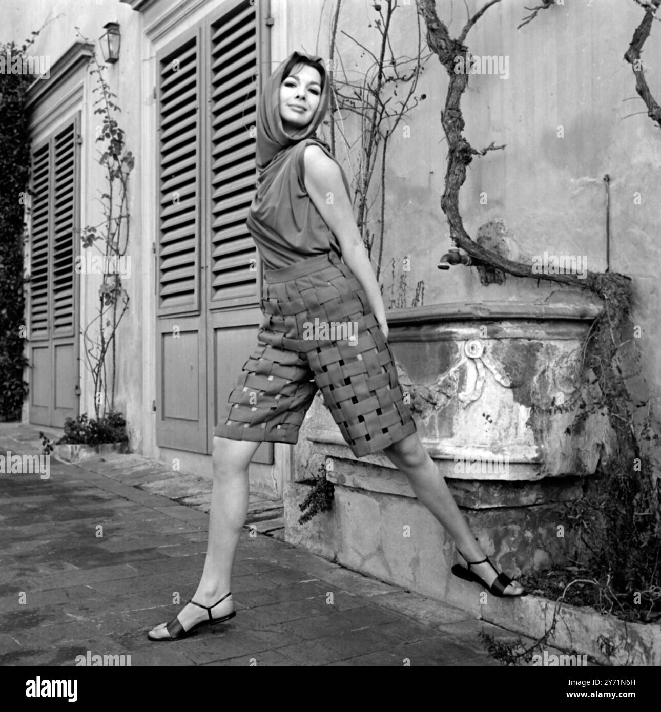 Sopra il bikini ensemble Firenze, Italia: Un capo originale da indossare in riva al mare sopra un bikini costituito da una pipa di pantaloni lunghi al ginocchio realizzati con spalline rosse e blu intrecciate che lasciano piccole sezioni ' A Jour' e una camicetta senza maniche che forma un cappuccio a foro di porto intorno al viso. Anche in rosso e blu. La creazione proviene dalla collezione Primavera / Estate 1965 di Lucrezia di Firenze. 20 gennaio 1965 Foto Stock