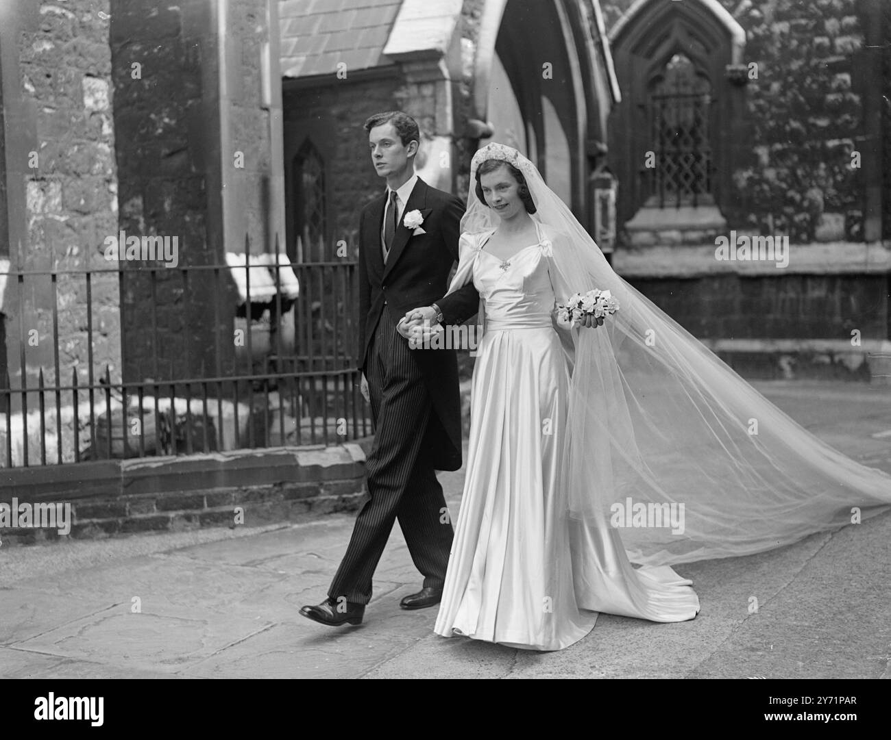 Matrimonio di San Michele. Indossando una copia dell'abito d'epoca indossava al matrimonio di suo zio - il conte Feversham , la signorina Anna Caroline Worthington , unica figlia della defunta Lady Diana Worthing e il defunto signor Greville Worthington , sposò il signor Oliver Patrick Miller Haskard , oggi a St. Michael's , Chester Square , Londra . Haskard è l'unico figlio del colonnello e della signora Dudley Haskard di Salisbury. La foto mostra : " matrimonio - chiusura " - con il suo abito a tutta lunghezza che scorre dietro di lei, la sposa lascia le mani stringendo le mani con lo sposo , dopo la cerimonia di oggi . 24 giugno 1948 Foto Stock
