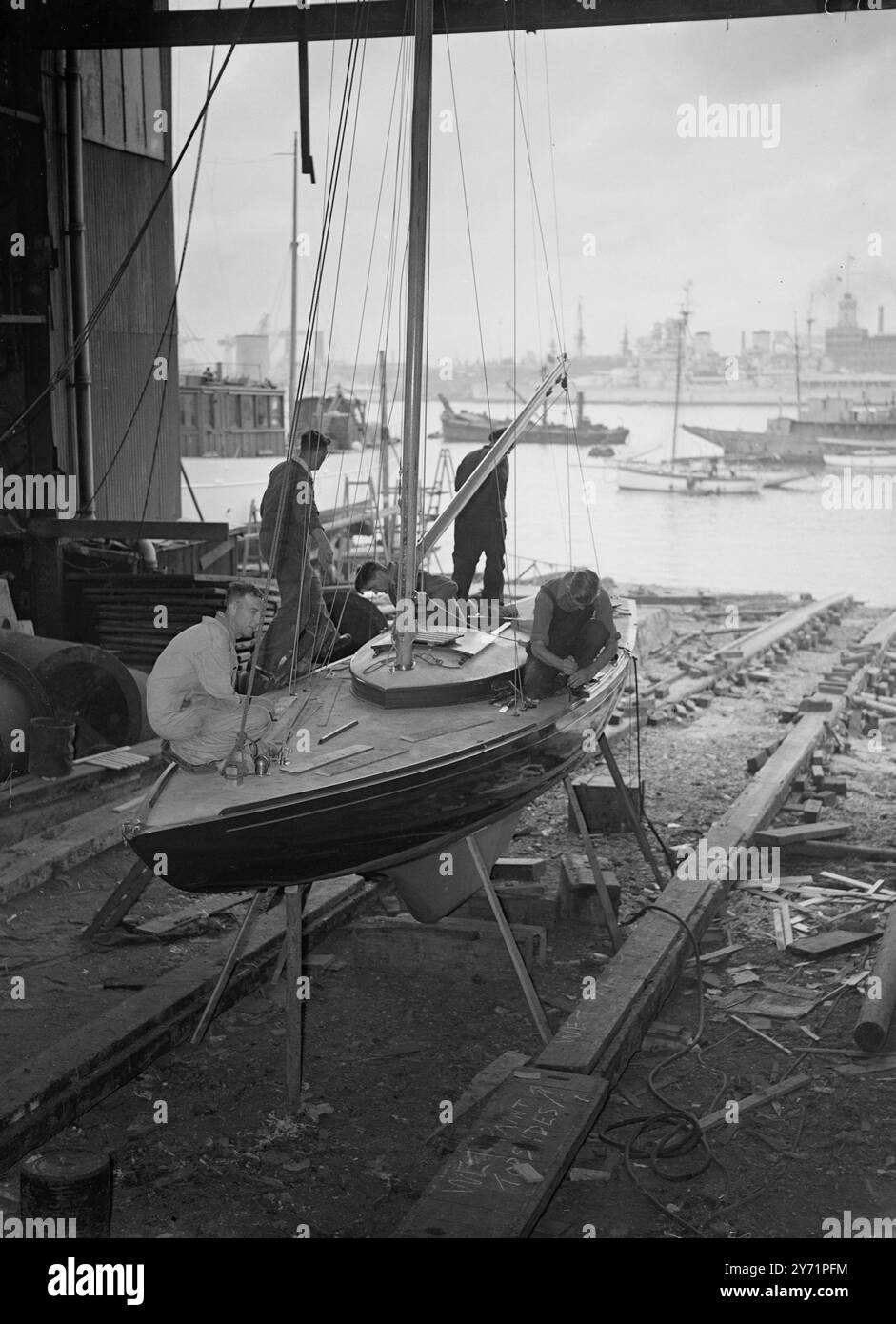 "Pronto per il buzz" - pronto per il Royal Racing Yacht. "Bluebottle", il piccolo yacht da corsa, che verrà presentato alle loro altezza reali, la Principessa Elisabetta e il Duca di Edimburgo, sta ascoltando il completamento a camper and Nicholson's Yard, Gosport, Hants. Immagini: Il nuovo yacht Royal Sailing 'Bluebottle', un regalo alla principessa Elisabetta e al duca di Edimburgo, dall'Island Sailing Club (Isola di Wight), le sta dando il tocco finale. H.M.S. 'Duke of York' e H.M.S. 'Victory' possono essere visti sullo sfondo. Giugno 29 1948 Foto Stock