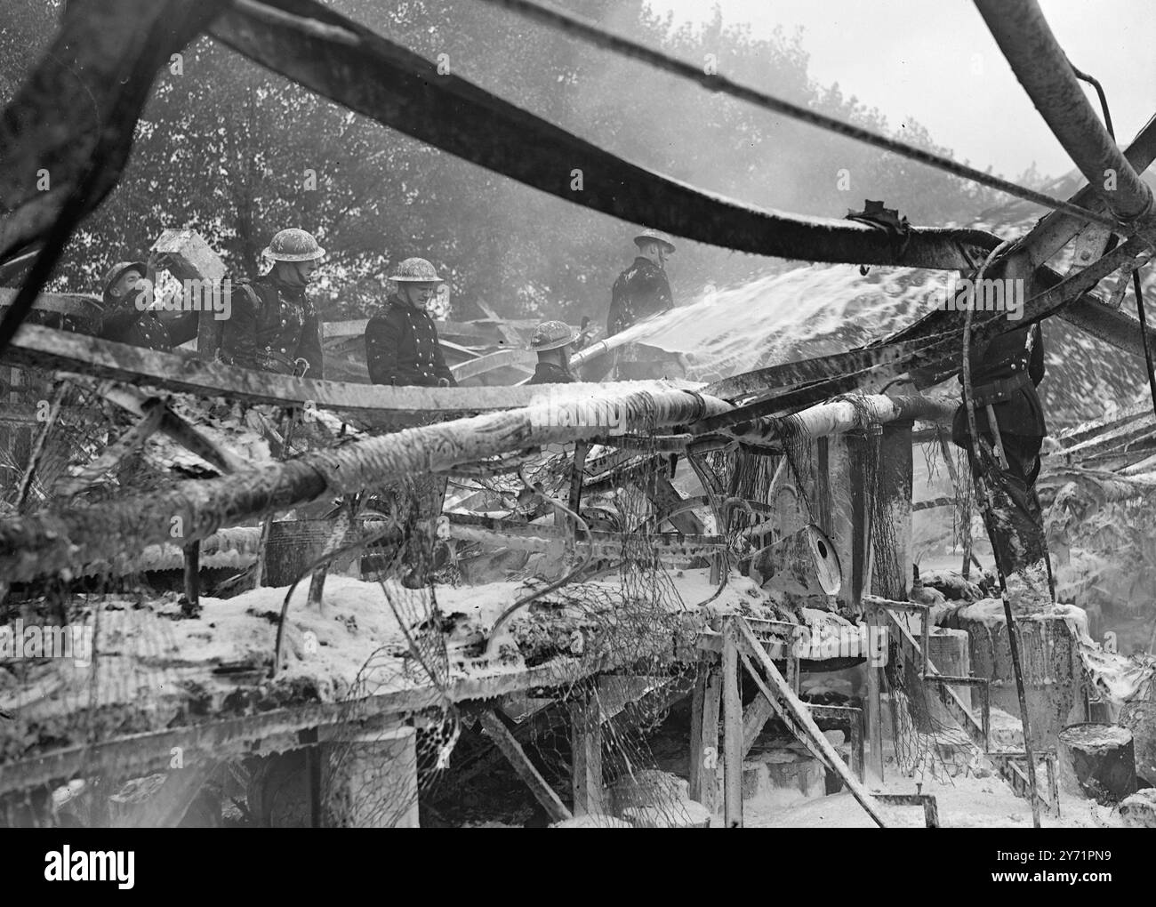 200 lasciare casa mentre la fabbrica si infiamma. Più di 200 persone hanno lasciato le loro case a Colindale, Middlesex, oggi, quando l'incendio ha infuriato per due ore presso la Titanine Ltd. Produttori di aeroplani a circa 800 metri dall'aeroporto Hendron RAF. Più di 60 pompieri che usavano schiuma aiutati dalla propria brigata, limitarono l'epidemia al negozio di vernici industriali. Centinaia di persone hanno guardato il fuoco da lontano, mentre le fiamme sono salite a 200 piedi e i barili di alcol butilico sono stati lanciati in aria mentre esplodevano. Molte persone che vivevano nel quartiere aprirono le finestre per evitare che il vetro si incrinasse. P Foto Stock