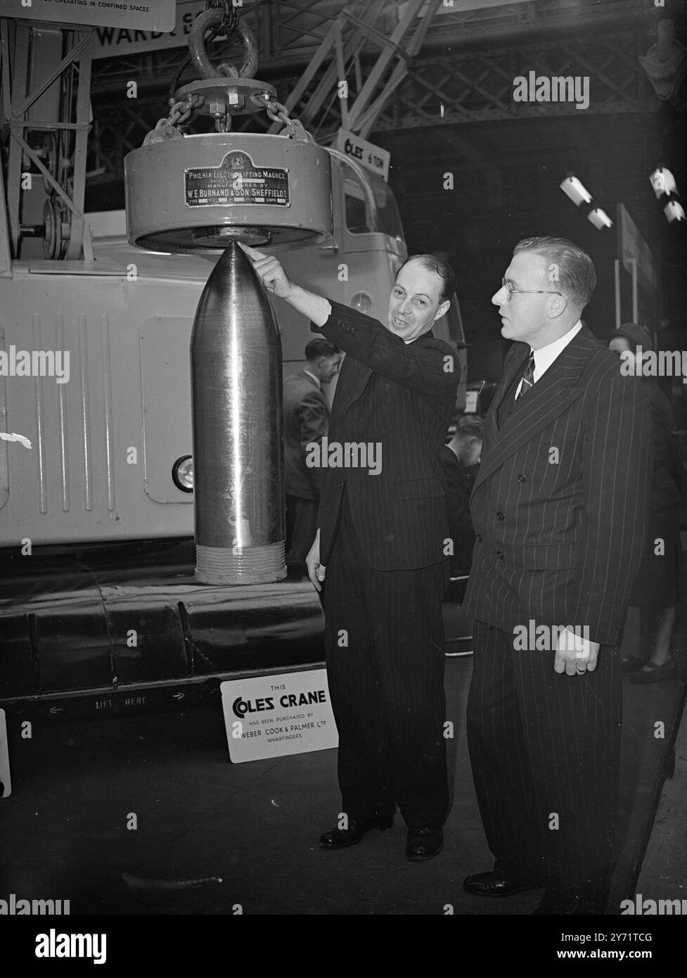 Mechanical Handling Exhibition la prima mostra e convezione nazionale di movimentazione meccanica è stata inaugurata oggi presso la National Hall di Olympia, Londra. L'immagine mostra: "Tocco magnetico" - JW Bernand, inventore del magnete elettronico, sottolinea al signor RLE Keates come la sua macchina sia in grado di sollevare un guscio di buone dimensioni durante una dimostrazione. 12 luglio 1948 Foto Stock