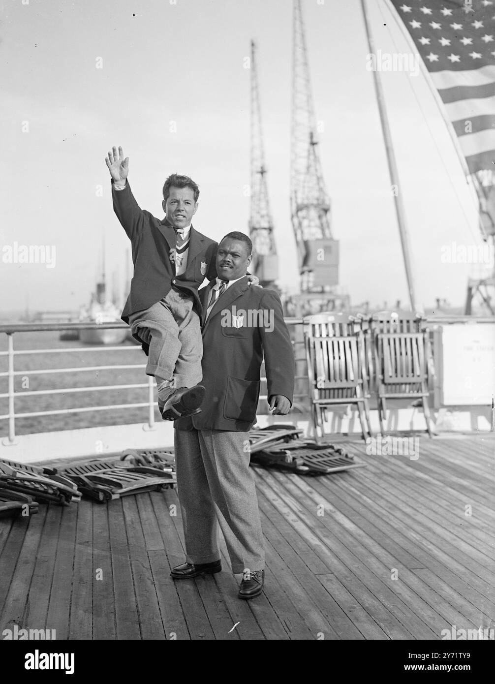 "Forza olimpica" - arrivano le Olimpiadi americane. John Davis - un membro della squadra olimpica americana arrivata a Southampton sulla SS 'America', solleva Joe De Pietro (peso bantam), campione del mondo di sollevamento pesi, per dargli un bell'aspetto della costa inglese. 21 luglio 1948 Foto Stock