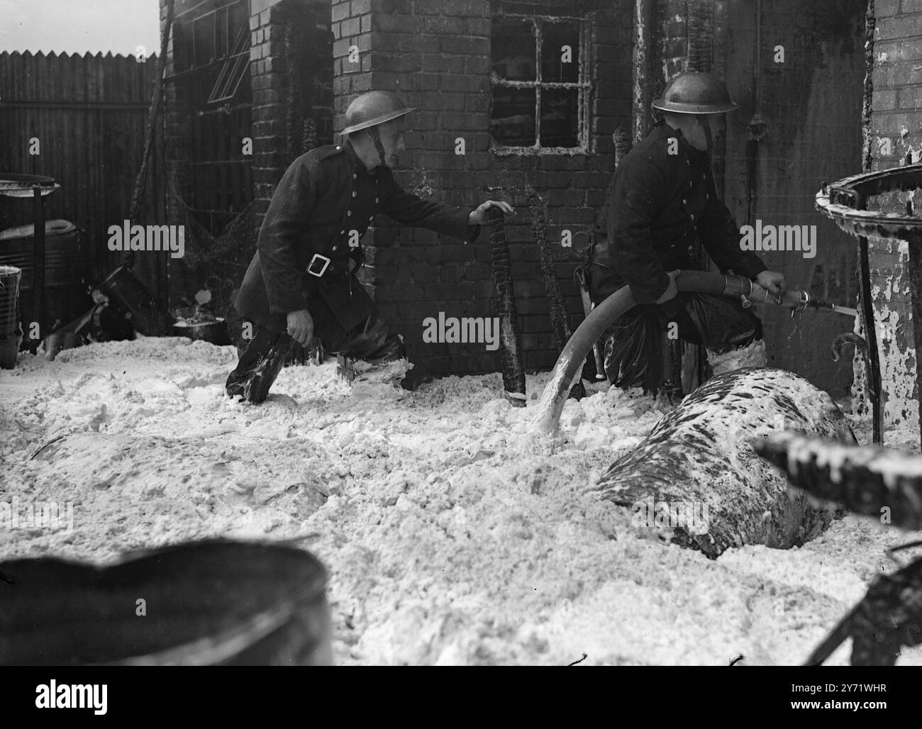 200 lasciare casa mentre la fabbrica si infiamma. Più di 200 persone hanno lasciato le loro case a Colindale, Middlesex, oggi, quando l'incendio ha infuriato per due ore presso la Titanine Ltd. Produttori di aeroplani a circa 800 metri dall'aeroporto Hendron RAF. Più di 60 pompieri che usavano schiuma aiutati dalla propria brigata, limitarono l'epidemia al negozio di vernici industriali. Centinaia di persone hanno guardato il fuoco da lontano, mentre le fiamme sono salite a 200 piedi e i barili di alcol butilico sono stati lanciati in aria mentre esplodevano. Molte persone che vivevano nel quartiere aprirono le finestre per evitare che il vetro si incrinasse. P Foto Stock