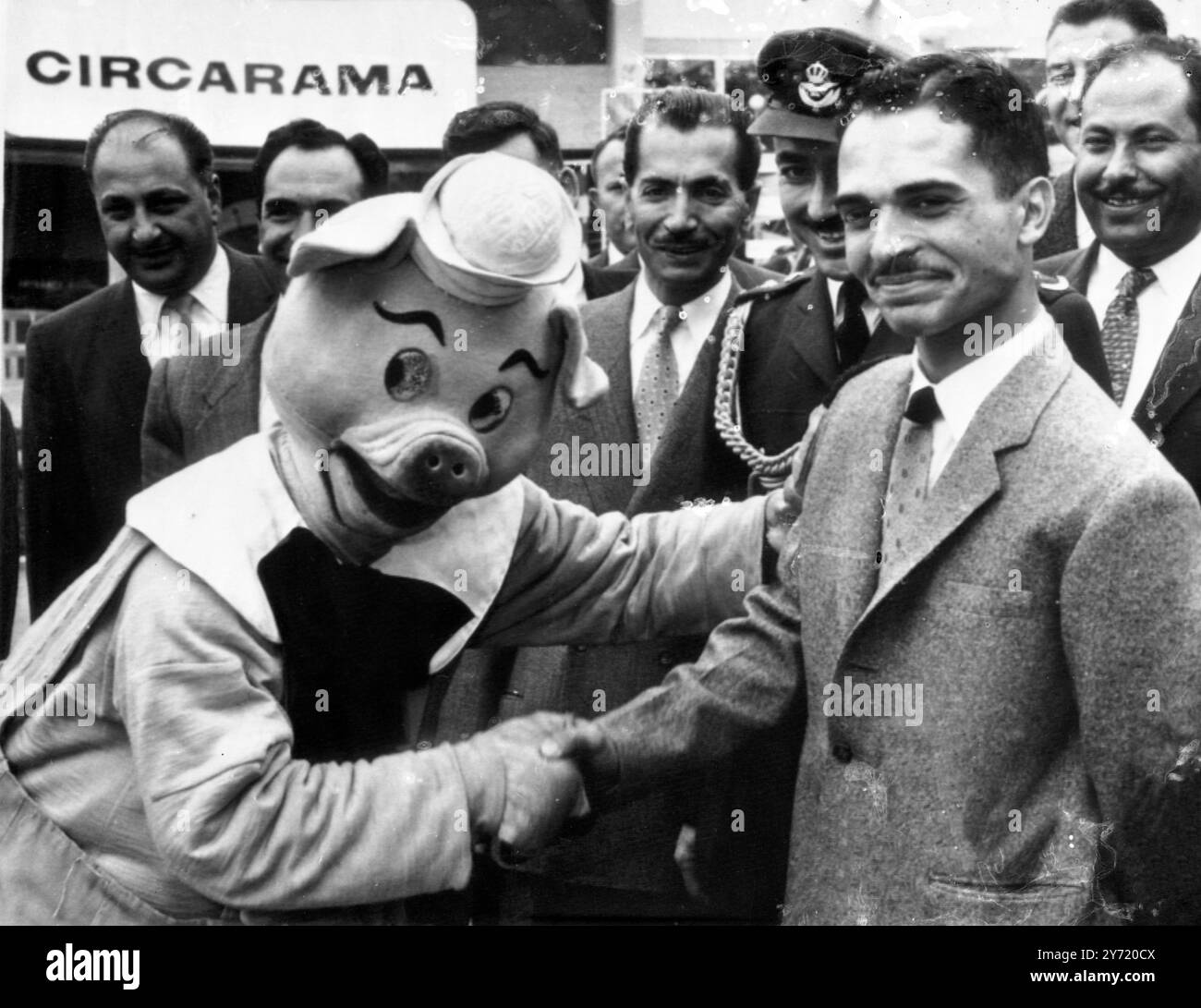 Hussein incontra "Porky" il maiale. Re Hussein di Giordania, ora in tour in America, incontra "Porky" il maiale, che gli offre uno zoccolo, mentre il re visita Disneyland Park. 6 aprile 1959 Foto Stock