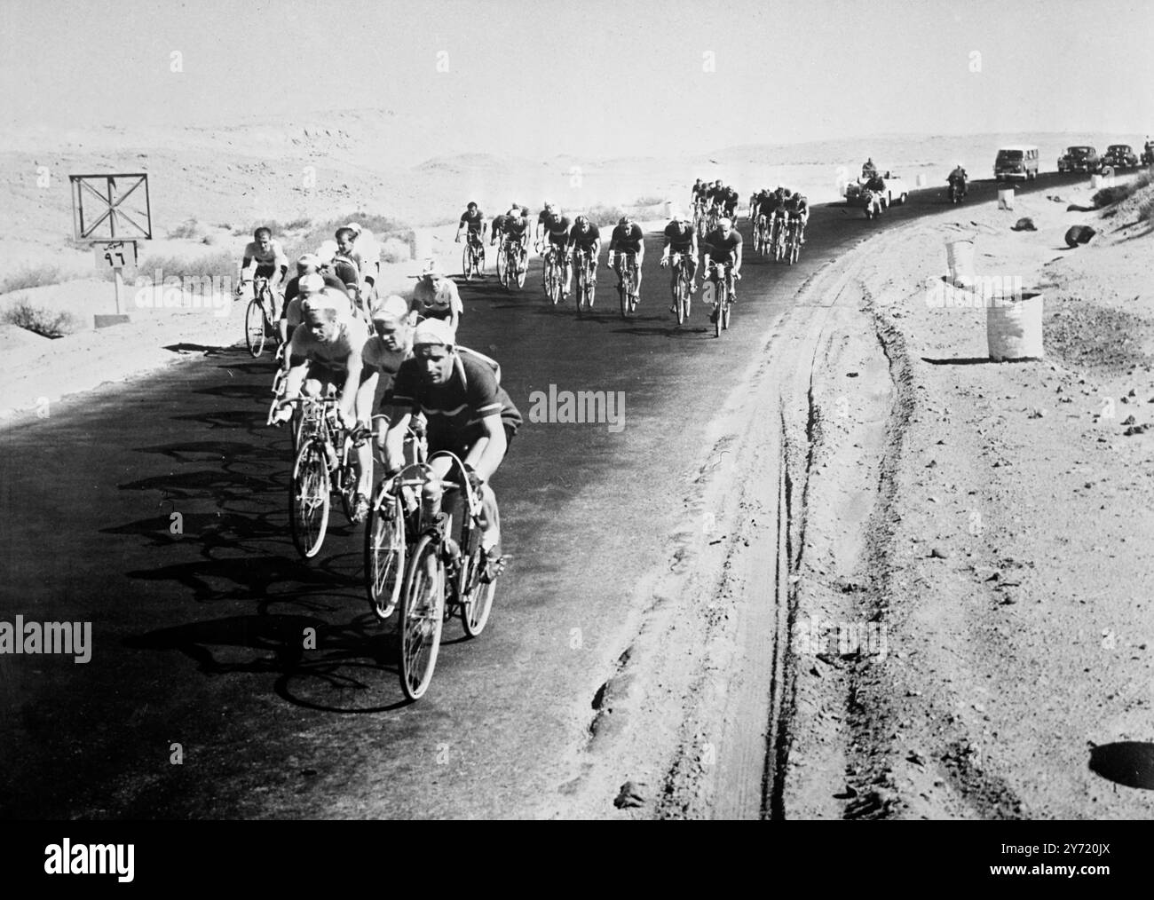 Cairo: I ciclisti pedalano lungo una strada desertica durante l'ultimo giro del tour dell'Egitto, da Suez al Cairo. La prima fila è composta da concorrenti bulgari e polacchi, mentre nella seconda fila sono danesi e tedeschi dell'Est. 28 gennaio 1956 Foto Stock