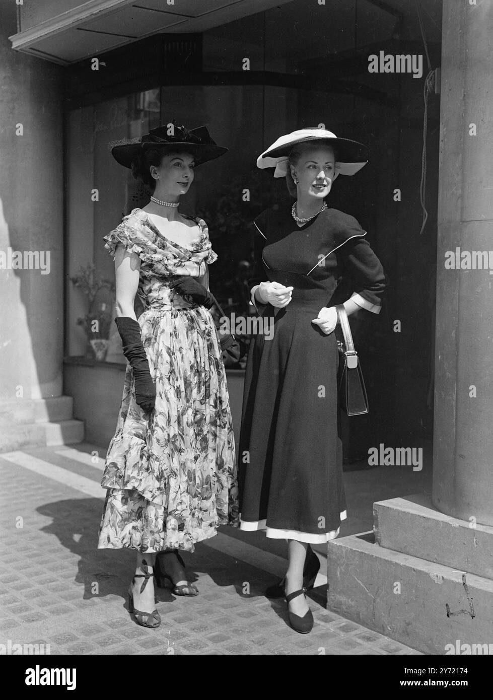 "FOR HOME AND AWAY" inaugurata dal Sig. Leif Egeland , alto Commissario per il Sudafrica , a Dorland House , Londra , è stata una nuova esposizione di tessuti per la casa e per l'esportazione da parte di produttori britannici, in Jersey di lana e lana stampata. Le immagini mostrano: Due attraenti creazioni estive. A sinistra è disponibile un abito Ascot " New length " in lana pregiata stampata. Ha uno scollo in fichu a spalla. L'abito in Jersey di lana nera a destra è rifinito con grosgrain bianco. La linea della spalla arrotondata si ripete sotto il busto, da dove la vita sottile e la gonna completa si inseriscono e seguono una linea ininterrotta. 29 aprile 194 Foto Stock