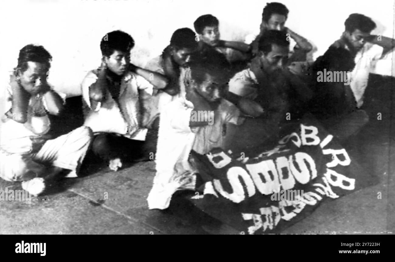 Comunisti catturati : Djarkarta , Indonesia ; Un gruppo di ribelli comunisti catturati dall'esercito al porto di Tanjong Priok sono mostrati accovacciati con le mani dietro la testa e la bandiera SOBSI si spalanca davanti a loro . 14 college universitari e altre istituzioni di istruzione superiore in Indonesia sono stati temporaneamente chiusi a causa della crisi politico-militare. Due movimenti studenteschi di influenza comunista sono stati sospesi per aver partecipato attivamente al recente tentativo di colpo di stato . 13 ottobre 1965 Foto Stock