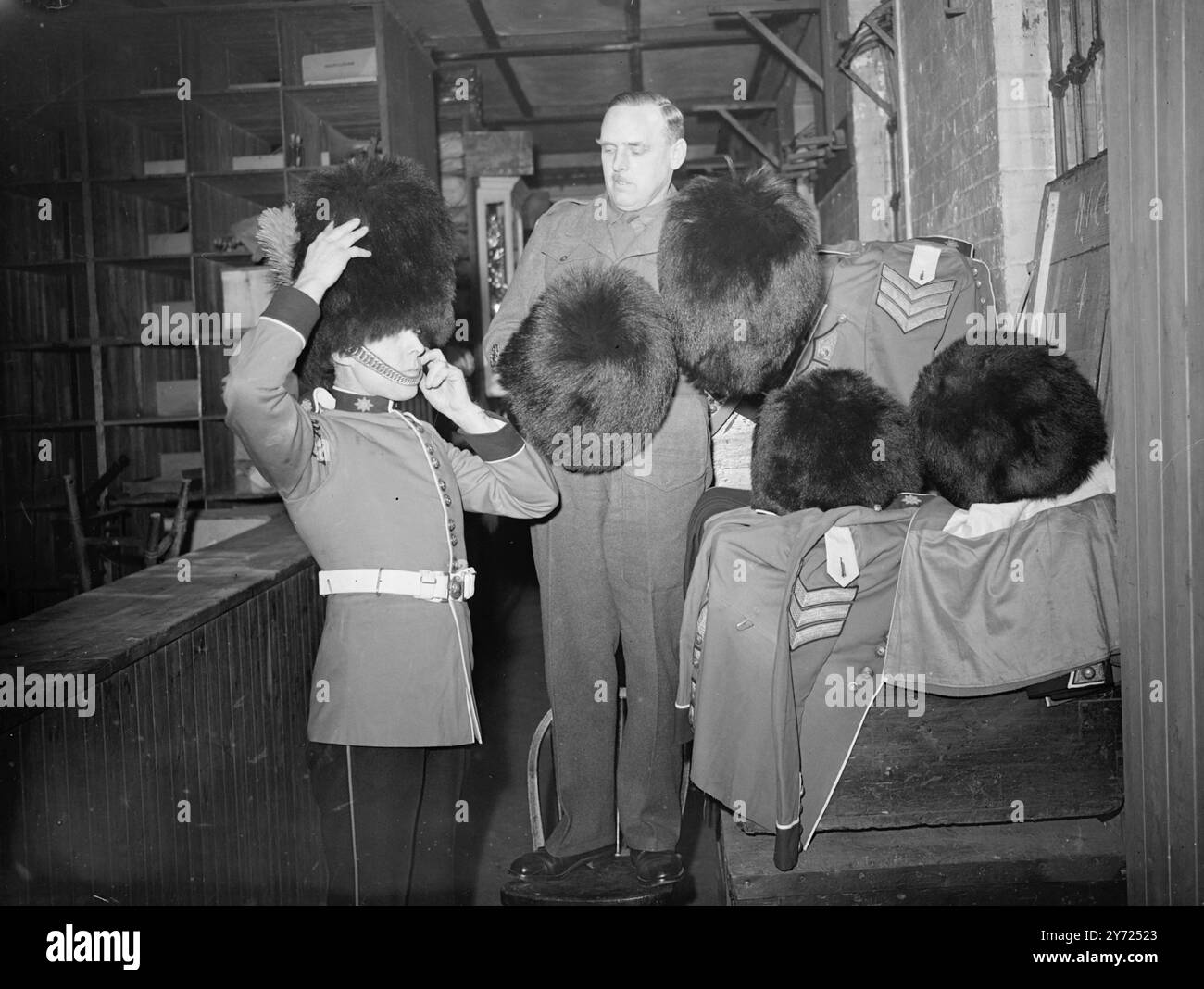 Con l'ordine che consente di nuovo uniformi complete per la Brigata delle guardie, le brillanti uniformi scarlatte e dorate delle Coldstream Guards sono emerse dai tronchi d'acciaio del "Quartermaster's Store" a Chelsea Barracks, Londra. H.. M il Re ha approvato il ritorno dell'abito completo e le pittoresche uniformi saranno viste per la prima volta dal 1939 al Trooping of the Colour il 10 giugno prossimo. Un'uniforme completa per un ufficiale della Guardia oggi costa tra le 400 e le 500 sterline. Le immagini mostrano: R.Q.M.S Robins delle Coldstream Guards, lancia un'uniforme del Sergente Quarter Master della compagnia su cui provare Foto Stock