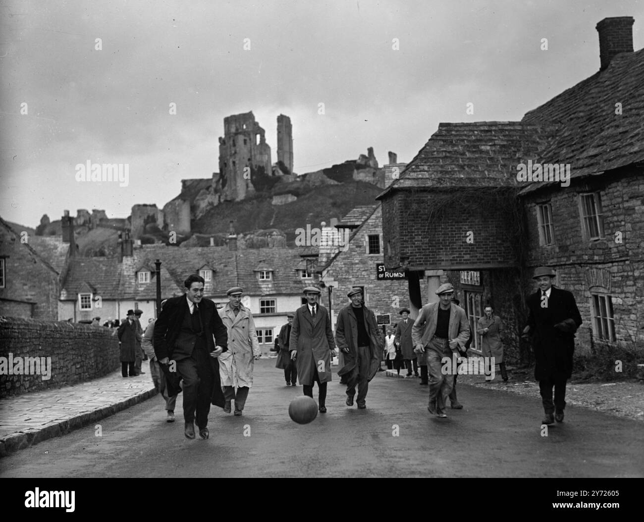 Cerimonia del martedì grasso, celebrata al castello di Corfe. I lavoratori della pietra di Purbeck si sono incontrati all'ombra dell'antico castello di Corfe per la loro cerimonia del martedì grasso per preservare il loro diritto di cava la famosa pietra, e oggi (martedì) è stata portata avanti la tradizione onorata nel tempo. Il momento culminante della cerimonia dei marmi è il calcio di una partita di calcio cosparsa di pepe attraverso antichi diritti di passaggio. Le immagini mostrano: L'antico castello di Corfe sullo sfondo, i quarrymen di Purbeck calpestano il peperoncino sparso di calcio per le strade, nell'odierna cerimonia del martedì grasso. 10 febbraio 1948 Foto Stock
