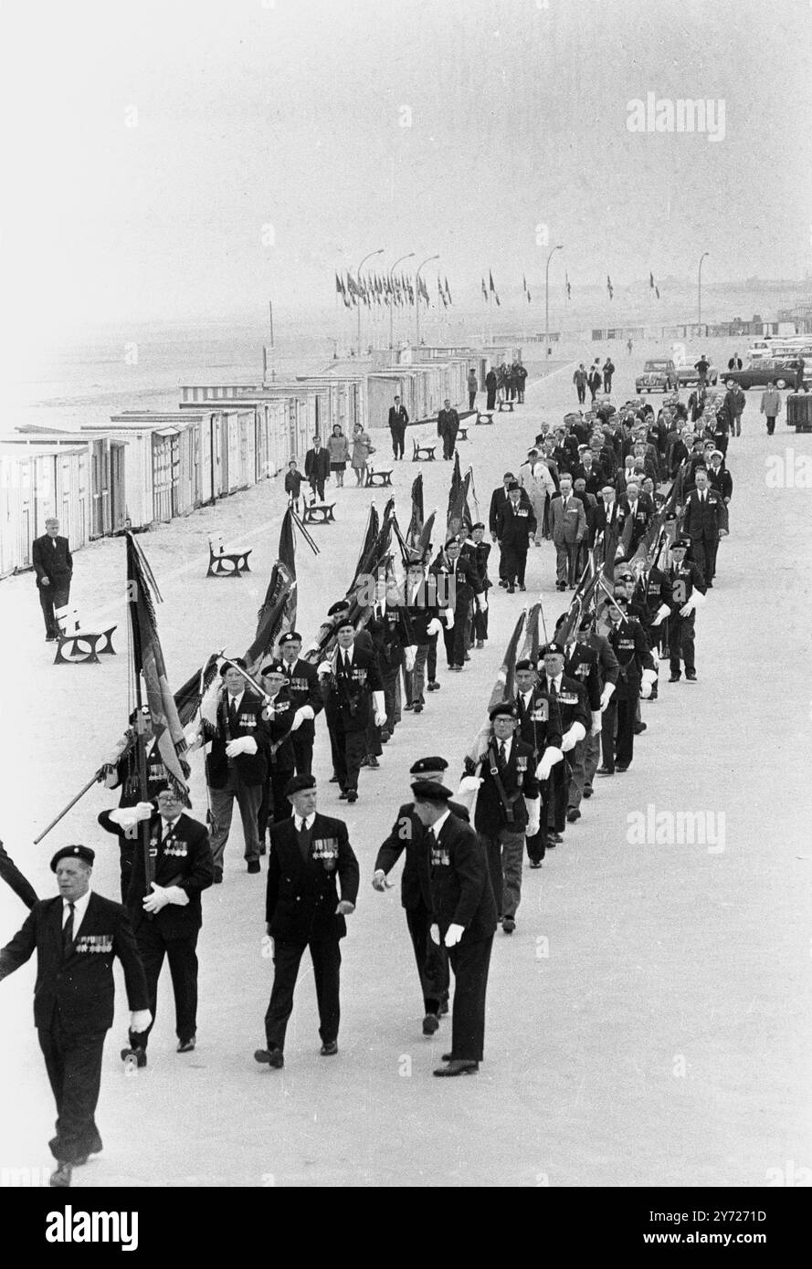 Con medaglie di servizio scintillanti sulle loro tute ben pressate , veterani inglesi , francesi e belgi della storica evacuazione della forza Expenditionaria britannica dalle spiagge di Dunkirk durante i giorni bui del 1940 giugno , marciate lungo il lungomare di Dunkirk il 5 giugno , durante le celebrazioni in occasione del 25° anniversario dell' incredibile evacuazione . Circa 400 uomini dei 337 131 che furono salvati dalle spiagge ( viste sullo sfondo ) , presero parte ad un servizio di memoria di fronte al semplice memoriale alleato sulle dune di sabbia , Dunkerque , Francia . 7 giugno 1965 Foto Stock