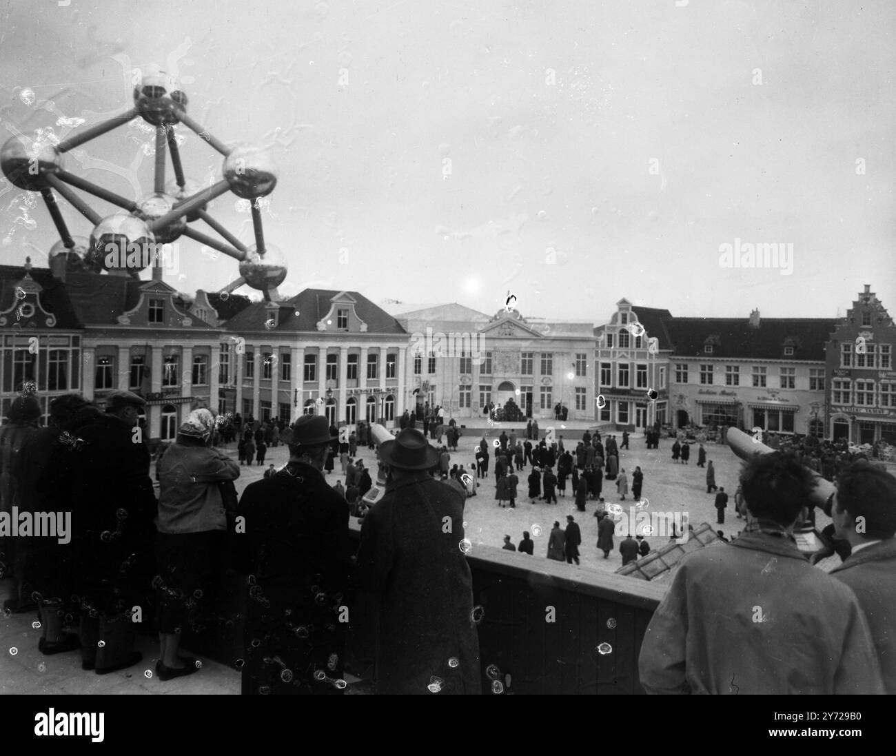 I visitatori della Fiera Mondiale di Bruxelles del 1958, inaugurata oggi, ammirano la mostra del Belgio del 1900, mentre altri visitatori in primo piano utilizzano i telescopi per vedere l'enorme Atomium che torreggia sullo sfondo e su tutta la Fiera del Belgio. 17 aprile 1958 Foto Stock