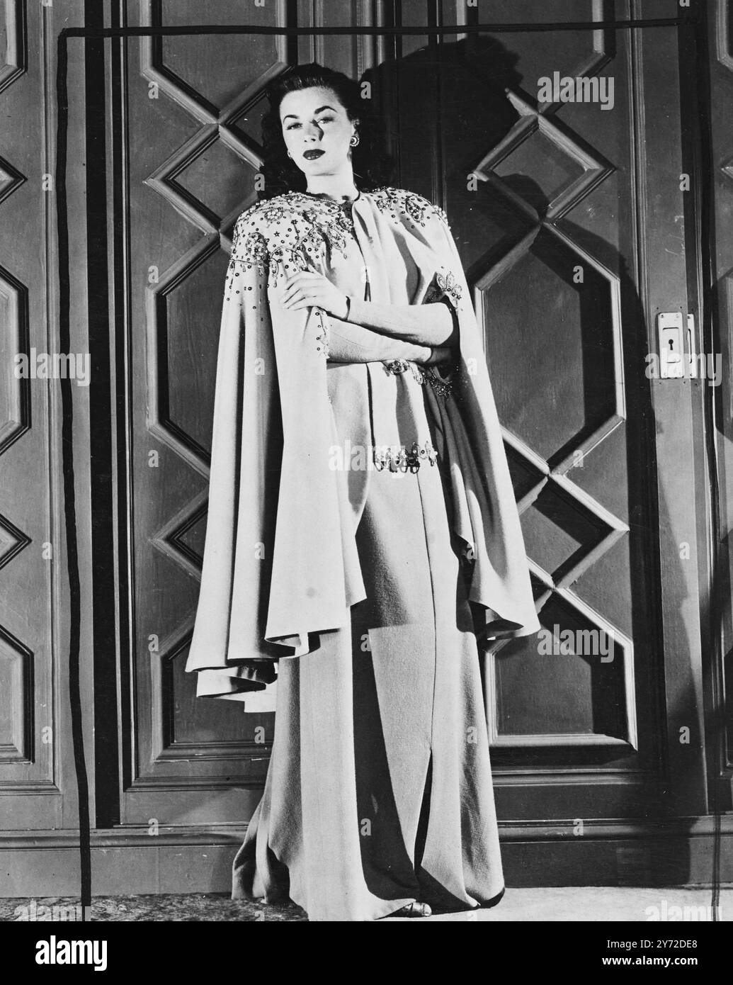 La ragazza che è venuta a cena. La star della Columbia Marguerite Chapman indossa un abito da sera in tessuto di lana bianca e un mantello, decisamente fuori dalla classe di austerità. Jewelembroiders in un materiale da caffe' au lait che non si pieghe né solletico, l'abito dà l'aspetto della ricca eleganza che un tempo era. 9 settembre 1947 Foto Stock