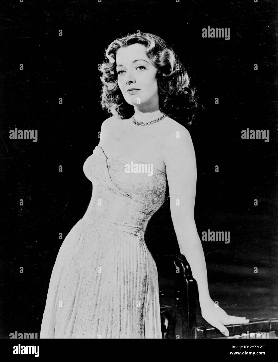 Vestita in modo glamour è l'affascinante star della mora e della cubia Ellen Drew, che è stata scelta per recitare al fianco di Larry Parks in un dramma romantico delle faide tra clan del XVIII secolo in Scozia chiamato The Swordsman. La Columbia Pictures voleva qualcuno che potesse indossare gli abiti del perriod con distinzione e, come potete vedere qui, Ellen era solo la ragazza. Indossa un'autentica stampa di un vecchio abito dello stilista Jean Louis. È in blu cielo, con un motivo di motivi floreali. La gonna a pieghe è dotata di imbottiture per il busto sui fianchi, mentre la parte superiore della spalla è curata per dare un'aria di distinzione a una vigilia Foto Stock