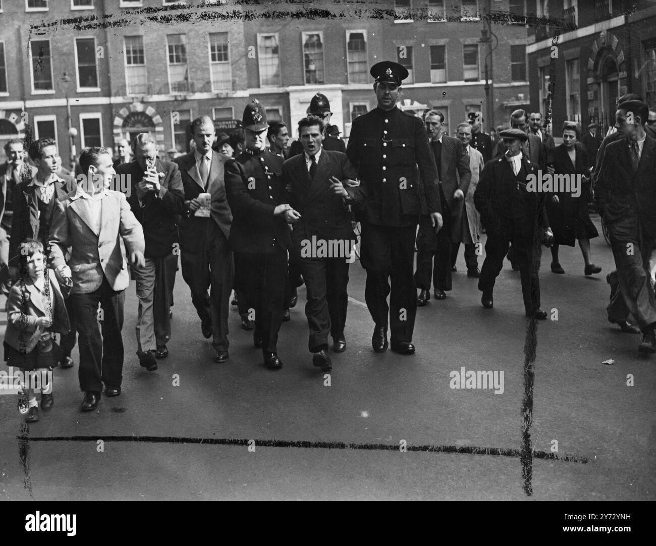 Un uomo e' stato arrestato fuori dall'hotel Ivanhoe, Bloomsbury, ed e' stato scortato alla stazione di polizia di Tottenham Court Road stamattina. L'hotel Ivanhoe e' stato preso da "squatters" ieri sera. Immagini: L'uomo arrestato viene portato via dagli agenti di polizia. 11 settembre 1946 Foto Stock