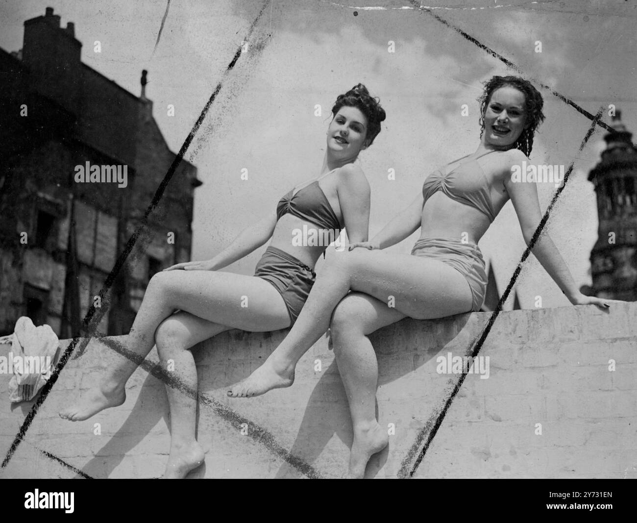 È ora di giocare. Due dei famosi Windmill Theatre, Londra, le bellezze si ritraggono tra uno spettacolo e l'altro per nuotare in vacanza nella piscina all'aperto Holborn. Jill Anstey (a sinistra) e Beth Ross trovano il muro un luogo utile per prendere il sole. 2 agosto 1946 Foto Stock