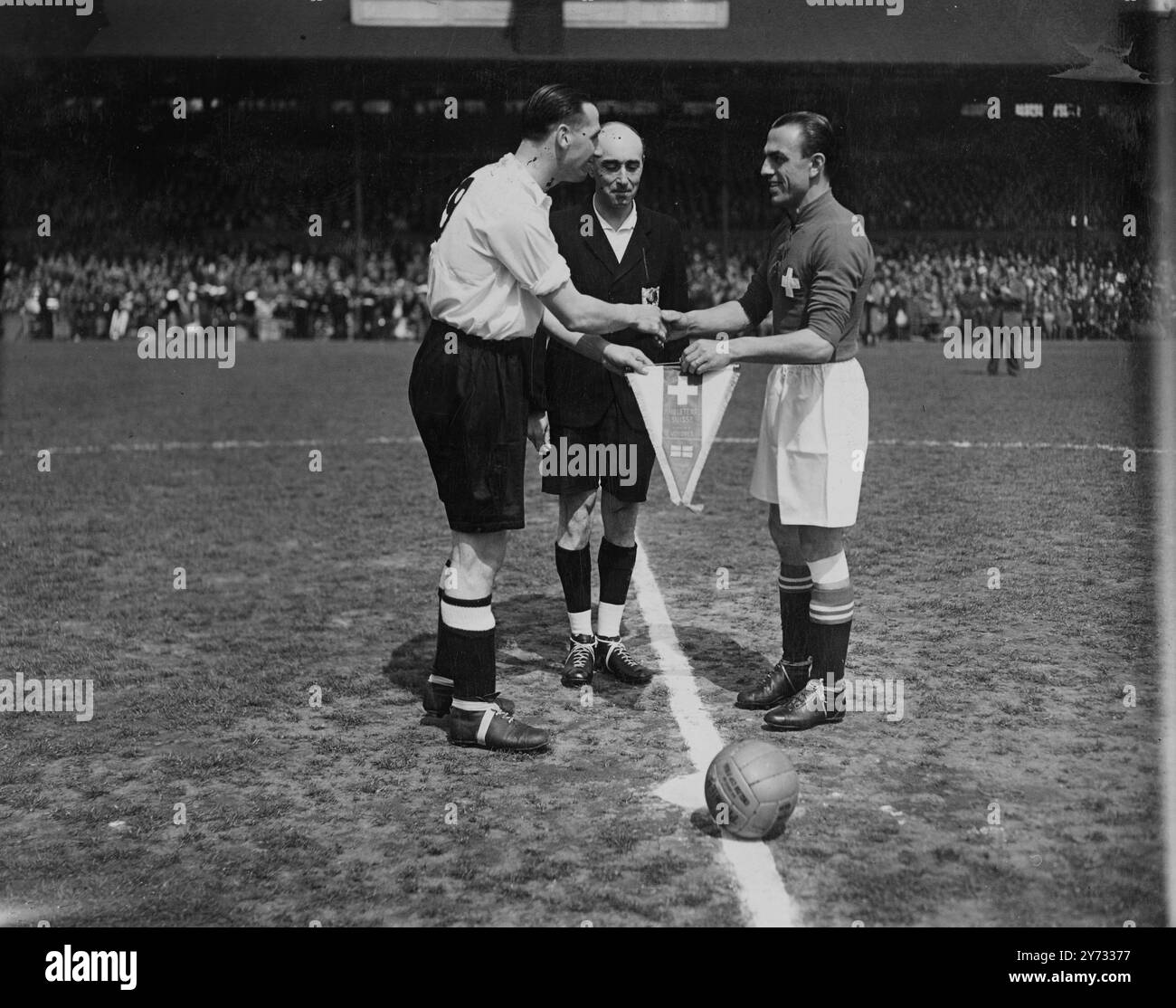 Una folla di 75.000 spettatori allo Stamford Bridge di Londra ha visto la partita internazionale di calcio tra Svizzera e Inghilterra. L'immagine mostra il capitano svizzero L. Amado (a destra) presenta una bandiera in segno della partita a Tommy Lawton, il capitano inglese. 11 maggio 1946 Foto Stock