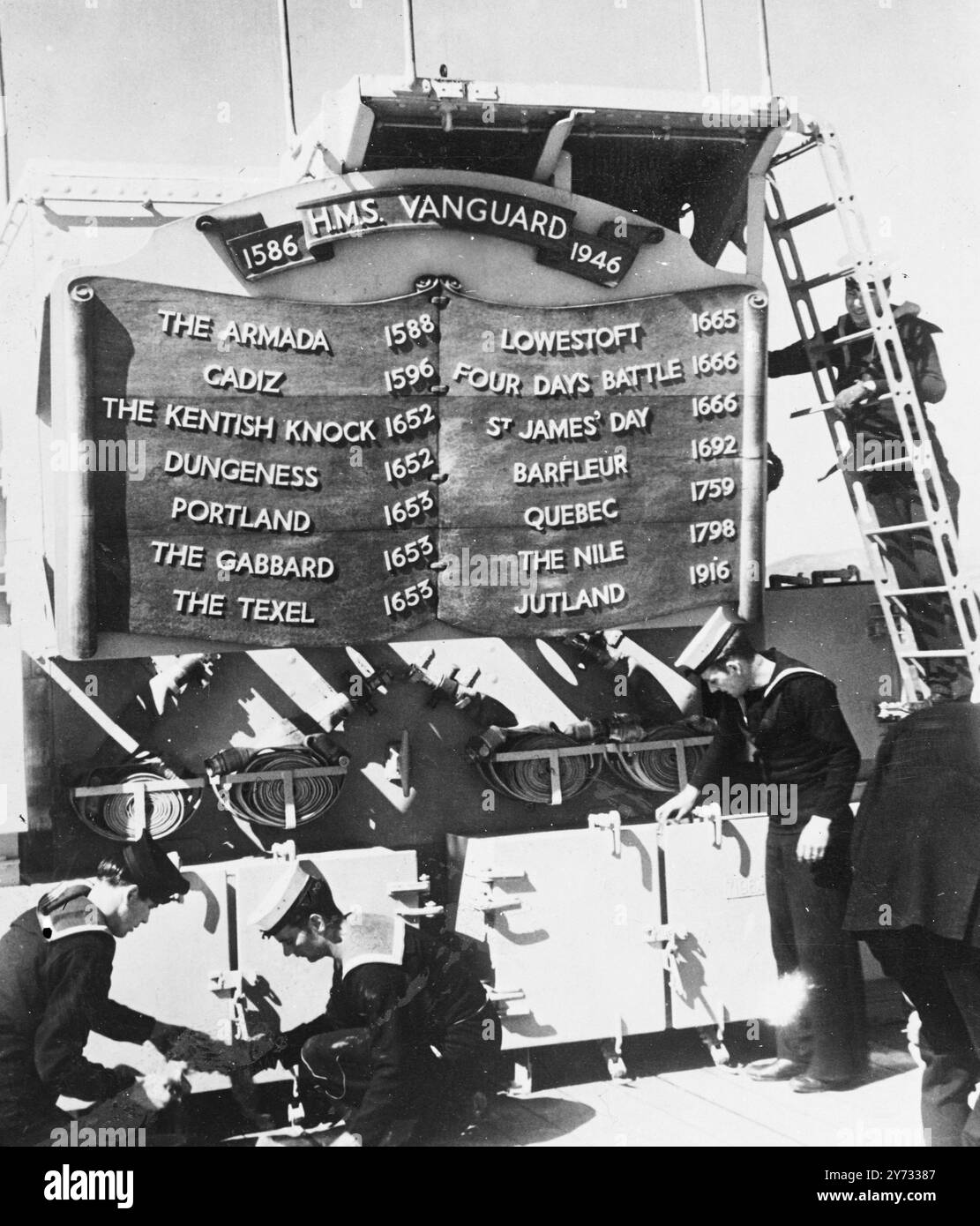 La HMS "Vanguard", la più grande nave da battaglia del mondo, ha rivelato alcuni dei segreti di oggi, giacché si trovava a un chilometro e mezzo circa dal transatlantico più grande del mondo, la SS "Queen Elizabeth", al largo di Greenock, in Scozia. I segreti della corazzata tedesca "Bismarck", dati dai prigionieri presi al suo affondamento, sono stati usati nella costruzione della "Vanguard". Il suo radar raccoglierà le navi a 100 miglia di distanza e gli aerei a una distanza di 140 miglia. L'immagine mostra lo stemma e gli onori di battaglia della HMS Vanguard del passato. 8 maggio 1946 Foto Stock