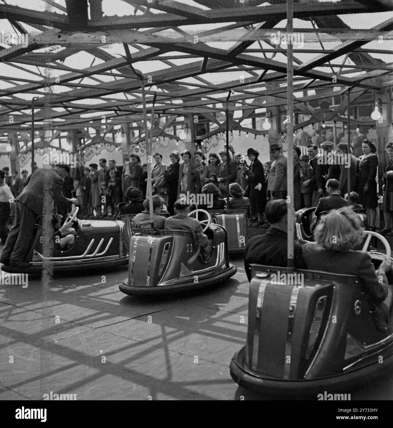 Persone che si divertono a fare giri in autoscontri all'Hampstead Heath Fair come altri guardano.1946 Foto Stock