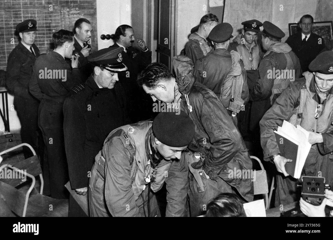 Malta : il capitano del gruppo L M Hodges , DSO, OBE, DFC (treccia d'oro sul cappello ) , interroga i membri dell'equipaggio dei bombardieri Valiant nella sala riunioni al loro ritorno da una sortita sull'Egitto . Il capitano Hodges comanda un'ala da bombardieri. Crisi di Suez 8 novembre 1956 Foto Stock