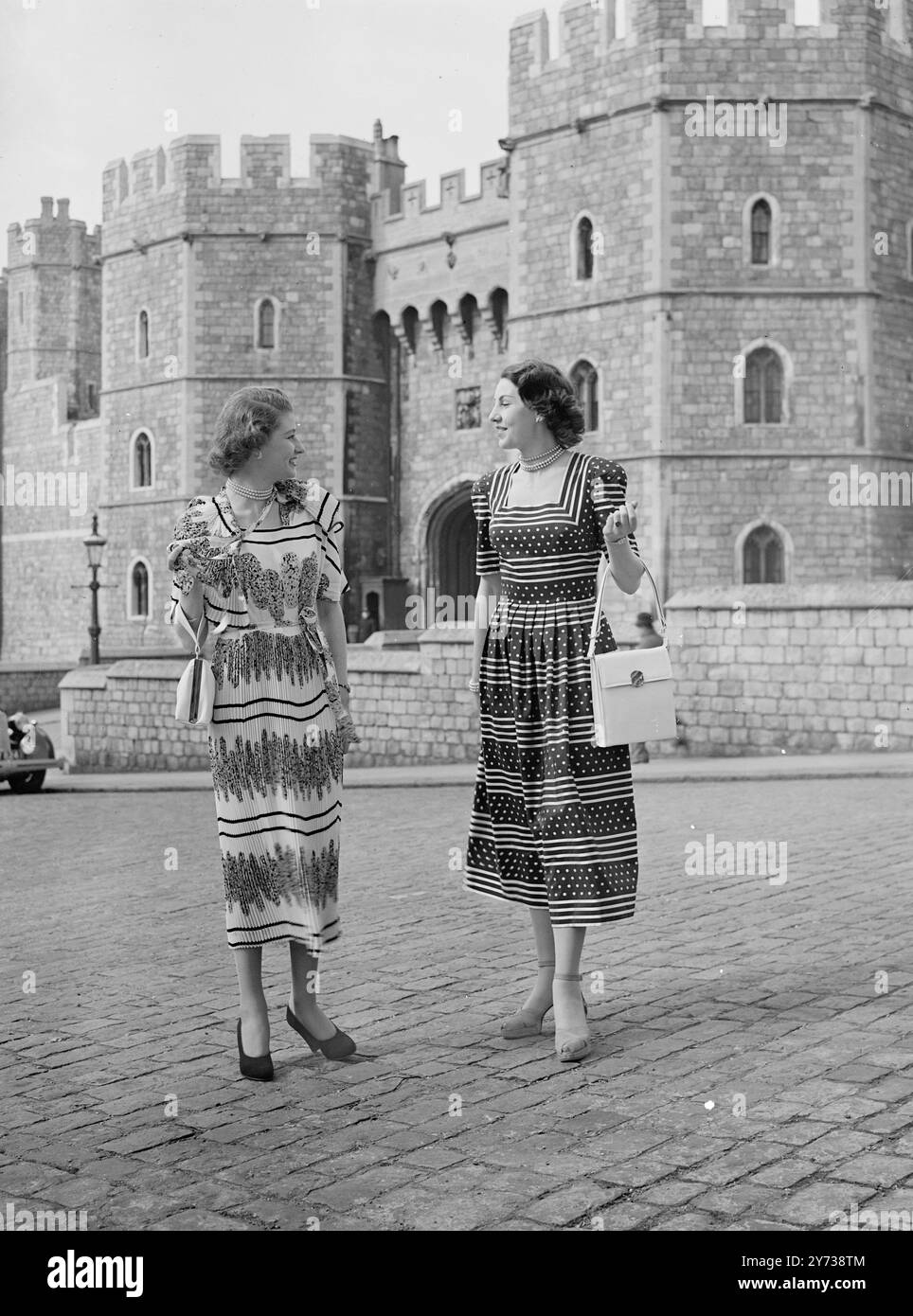 LE MODE NEL 'ROYAL BOROUGH'' il Castello di Windsor formavano uno sfondo per le ultime mode primaverili, come manichini che passeggiavano al sole tra le esposizioni alla sfilata di moda Caleys, all'ombra delle mura del Castello. PICTUTRE MOSTRA ;- Una camicia di seta pomeridiana stampata ( a sinistra ) , la gonna a pieghe della fisarmonica e il mantello staccabile sottolineano la brillante crepe stampata utilizzata per questo modello; . Sulla destra , un abito Taffeta navy a righe di raso grigio enfatizza il collo squadrato e la gonna a pieghe completamente non pressata . 10 marzo 1949 Foto Stock