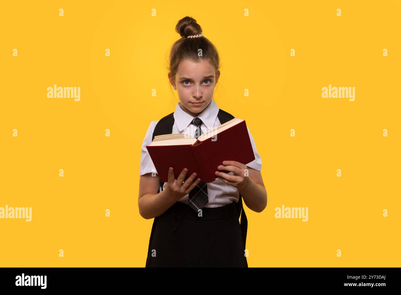 Una studentessa seria tiene un libro rosso aperto mentre è in piedi. Foto Stock
