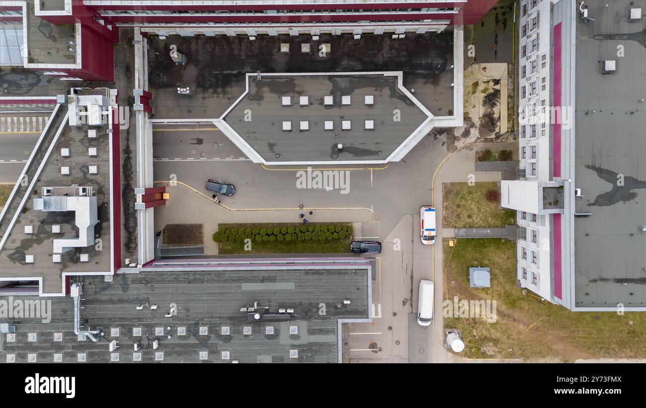 Vista aerea di un moderno ospedale con diversi edifici con tetti piani. Le strutture sono principalmente grigie e marroni, con alcuni veicoli parcheggiati Foto Stock