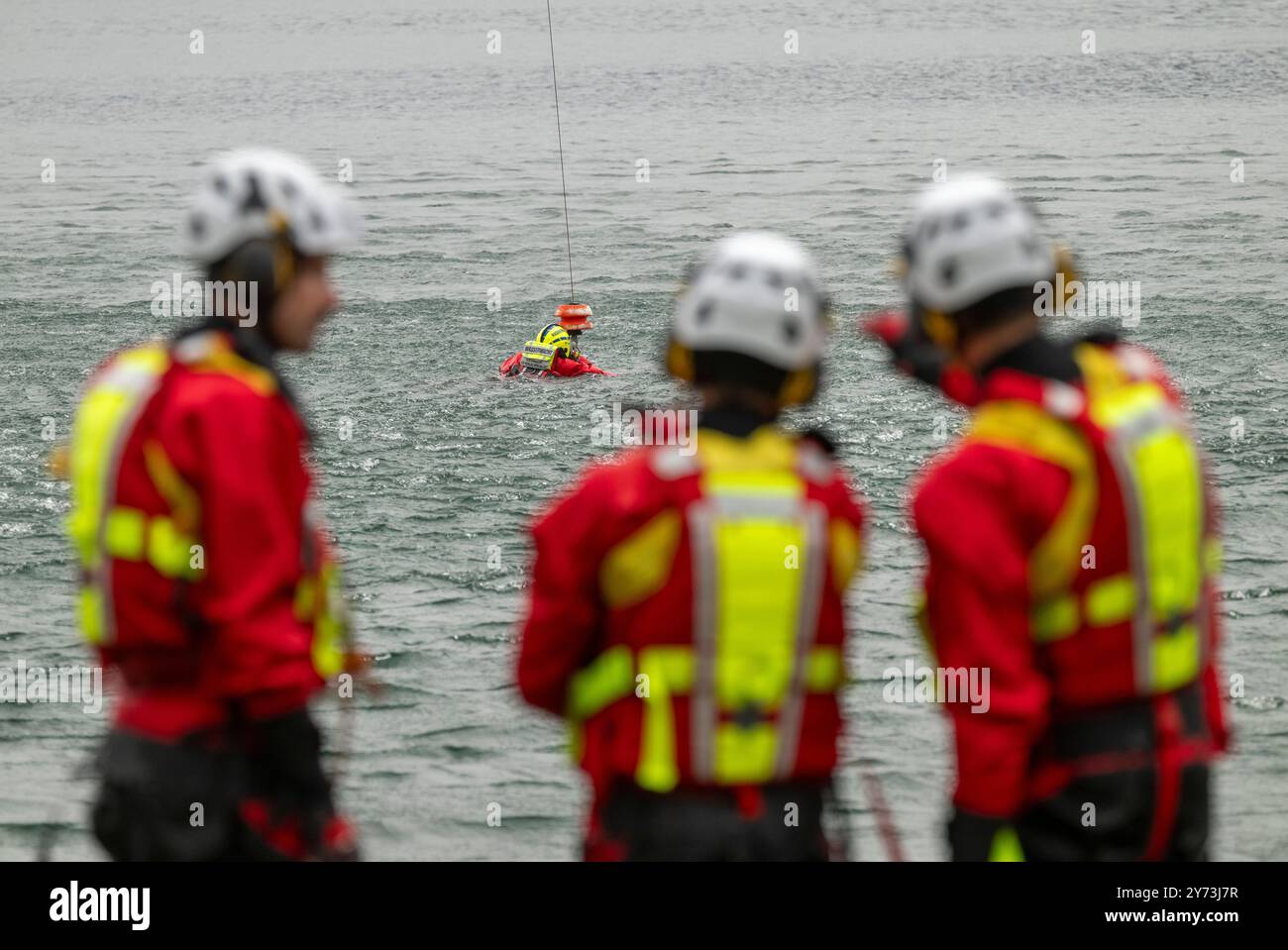 Walchensee, Germania. 27 settembre 2024. I membri dello squadrone di elicotteri di salvataggio ADAC e della squadra di salvataggio in acqua DLRG prendono parte all'addestramento di dispiegamento del verricello a Walchensee. Crediti: Peter Kneffel/dpa/Alamy Live News Foto Stock