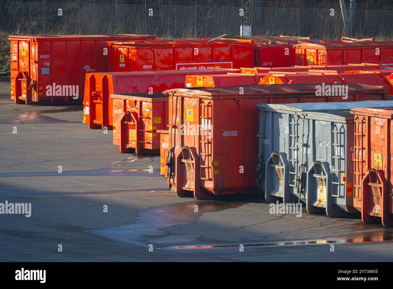 Gothenburg, Svezia - 12 febbraio 2023: Fila di contenitori per rifiuti irange e grigi su un retro Foto Stock