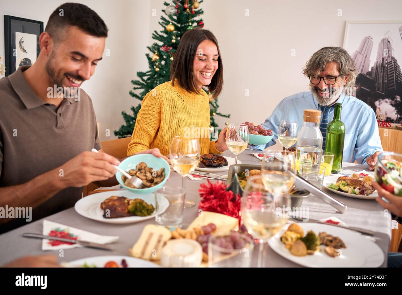 Una famiglia europea che ride e si diverte a festeggiare il Natale a casa seduto a tavola Foto Stock