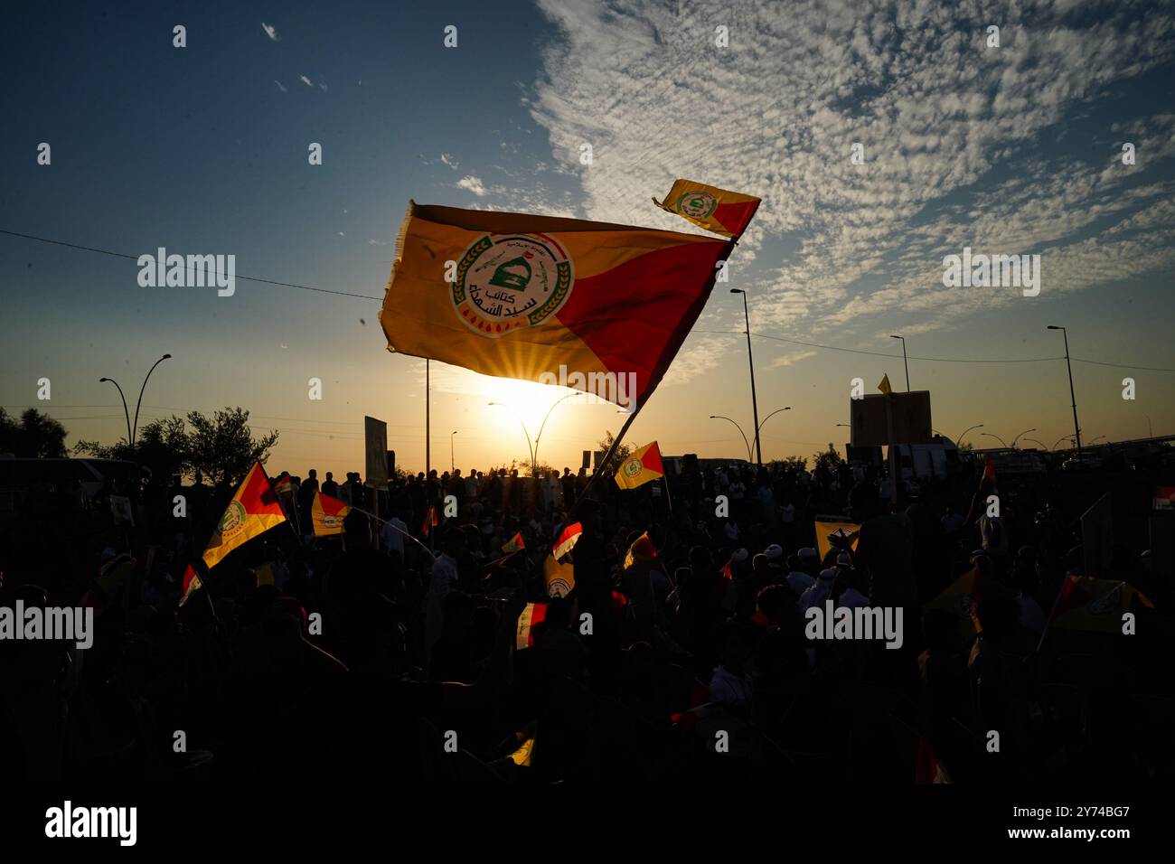 Mosul, Iraq. 27 settembre 2024. Un sostenitore sagomato della fazione armata Kataeb Sayyid al-Shuhada (membro delle forze di mobilitazione popolare al-Shaabi o PMF) tiene una bandiera durante una resistenza di solidarietà contro l'aggressione israeliana in Libano e Palestina vicino alla grande Moschea di Mosul (non in veiw) nella città di Mosul, Iraq. Credito: SOPA Images Limited/Alamy Live News Foto Stock