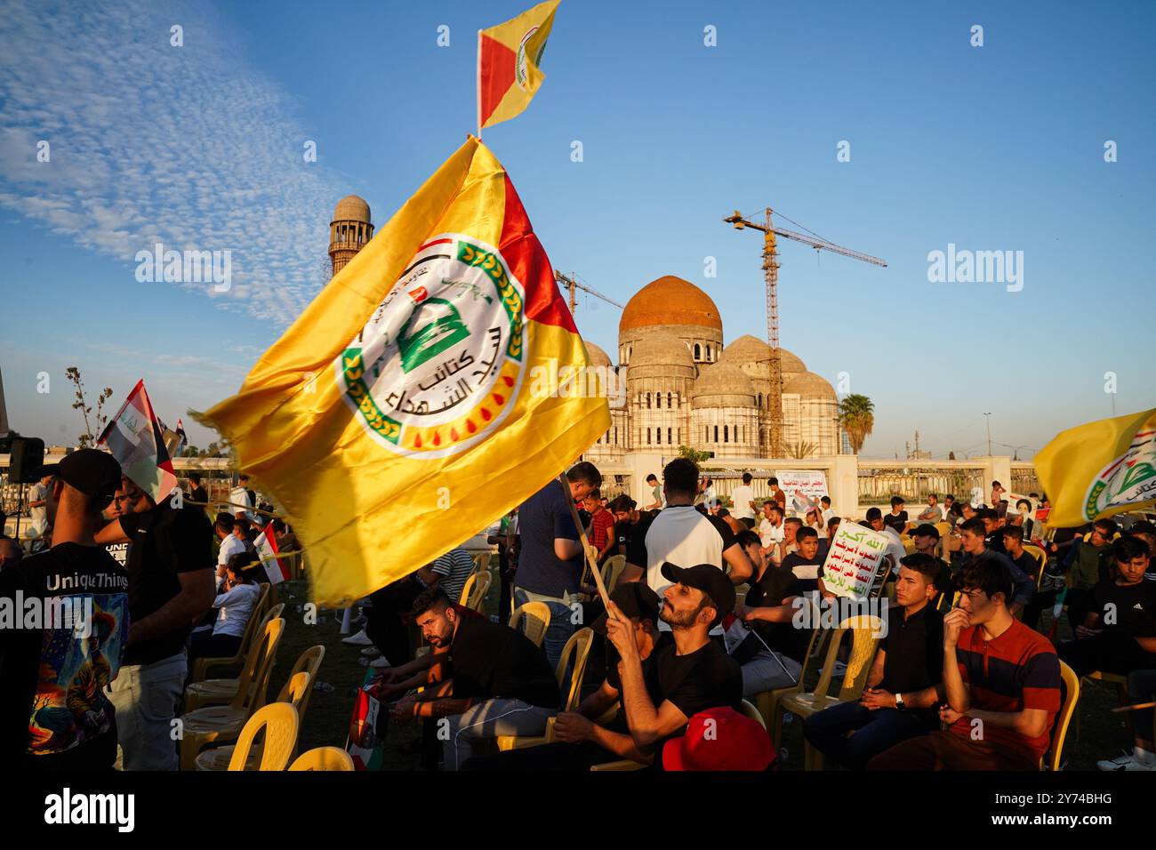 Mosul, Iraq. 27 settembre 2024. Sostenitore della fazione armata Kataeb Sayyid al-Shuhada (membro delle forze di mobilitazione popolare o PMF) detiene una bandiera durante una resistenza di solidarietà contro l'aggressione israeliana in Libano e Palestina vicino alla grande Moschea di Mosul nella città di Mosul. Credito: SOPA Images Limited/Alamy Live News Foto Stock