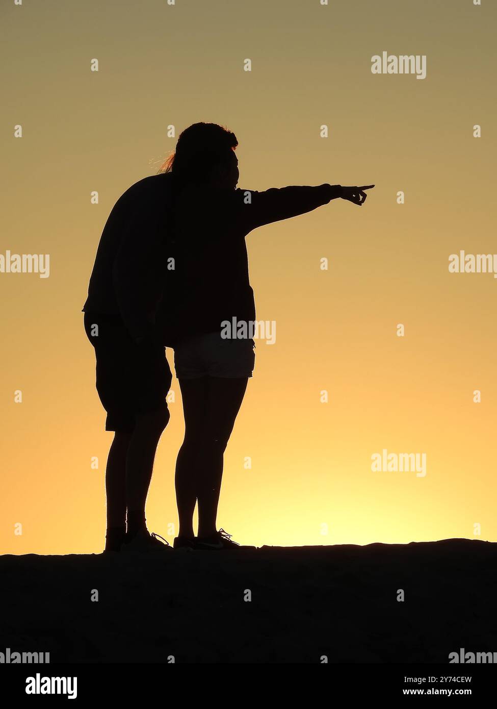 Una serie di accattivanti silhouette raffiguranti una coppia che condivide momenti teneri al tramonto, creando un'atmosfera serena e romantica. Foto Stock