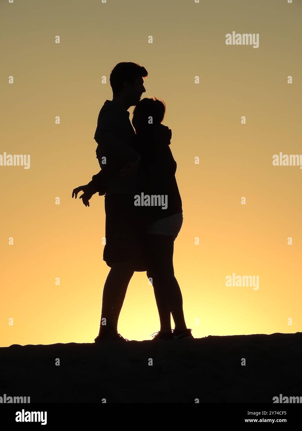 Una serie di accattivanti silhouette raffiguranti una coppia che condivide momenti teneri al tramonto, creando un'atmosfera serena e romantica. Foto Stock