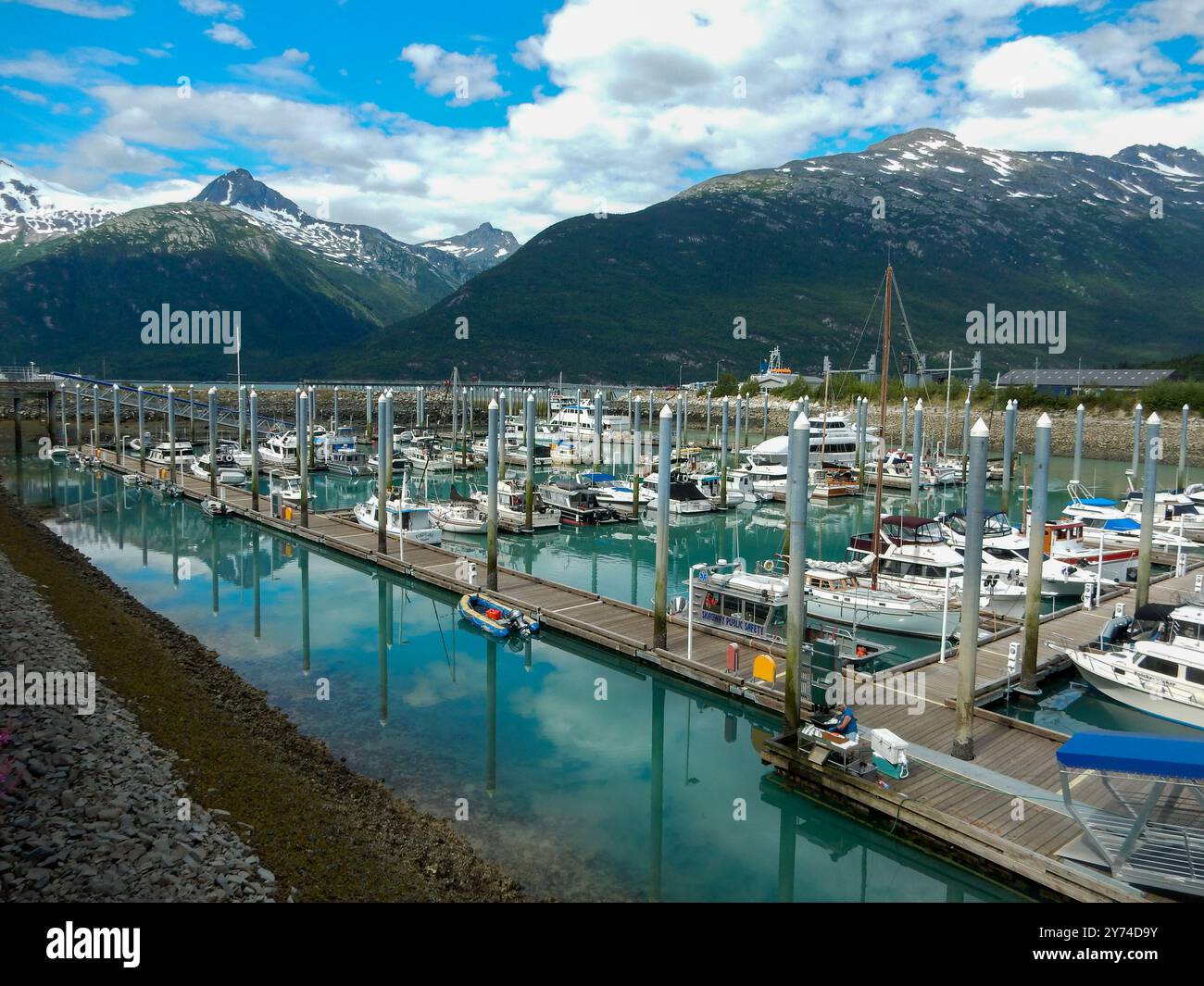 La barca ormeggia a Skagway, Alaska, all'ombra di un picco glaciale innevato. Foto Stock