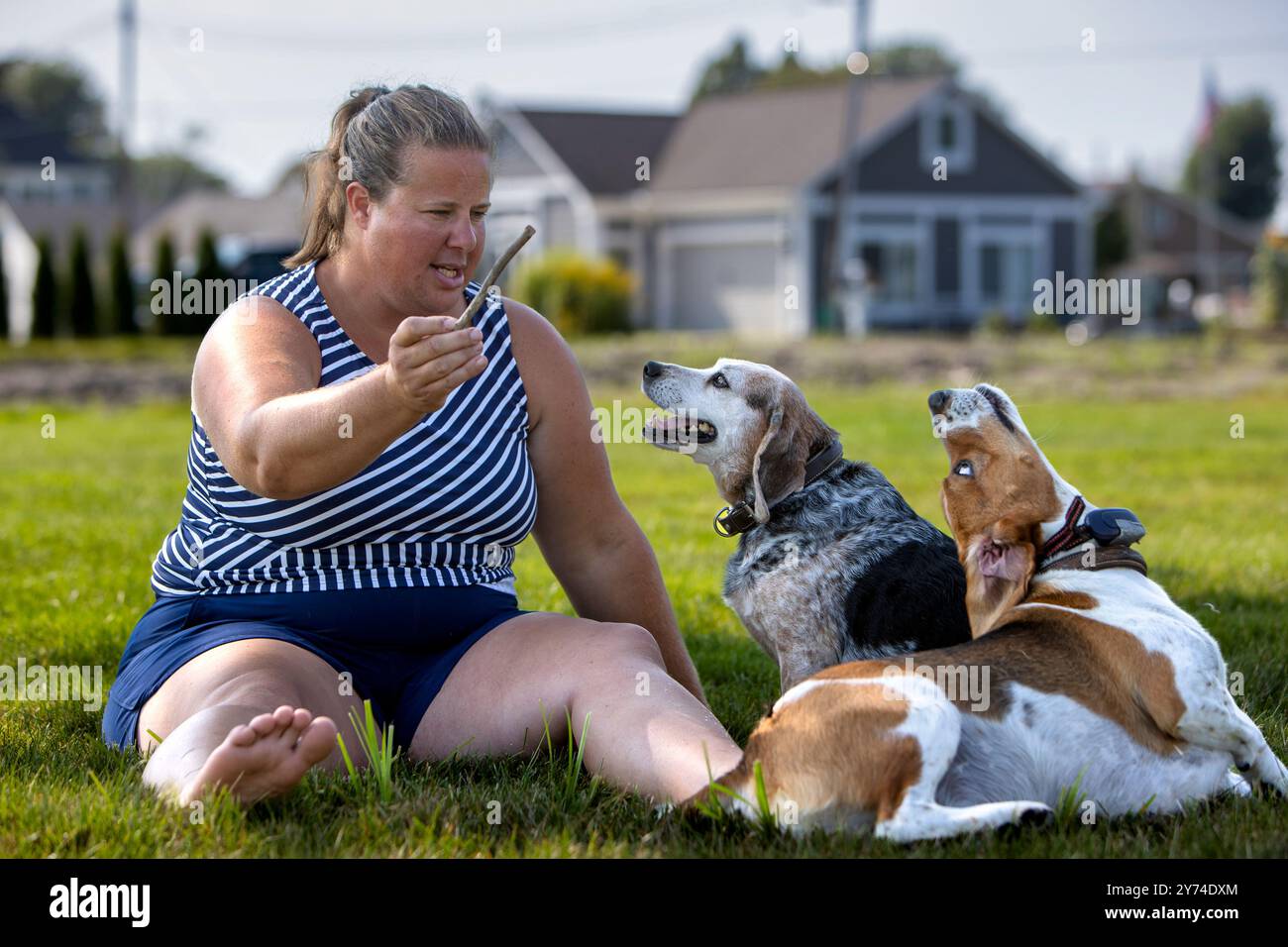 Una donna seduta su un prato con due cani. Foto Stock