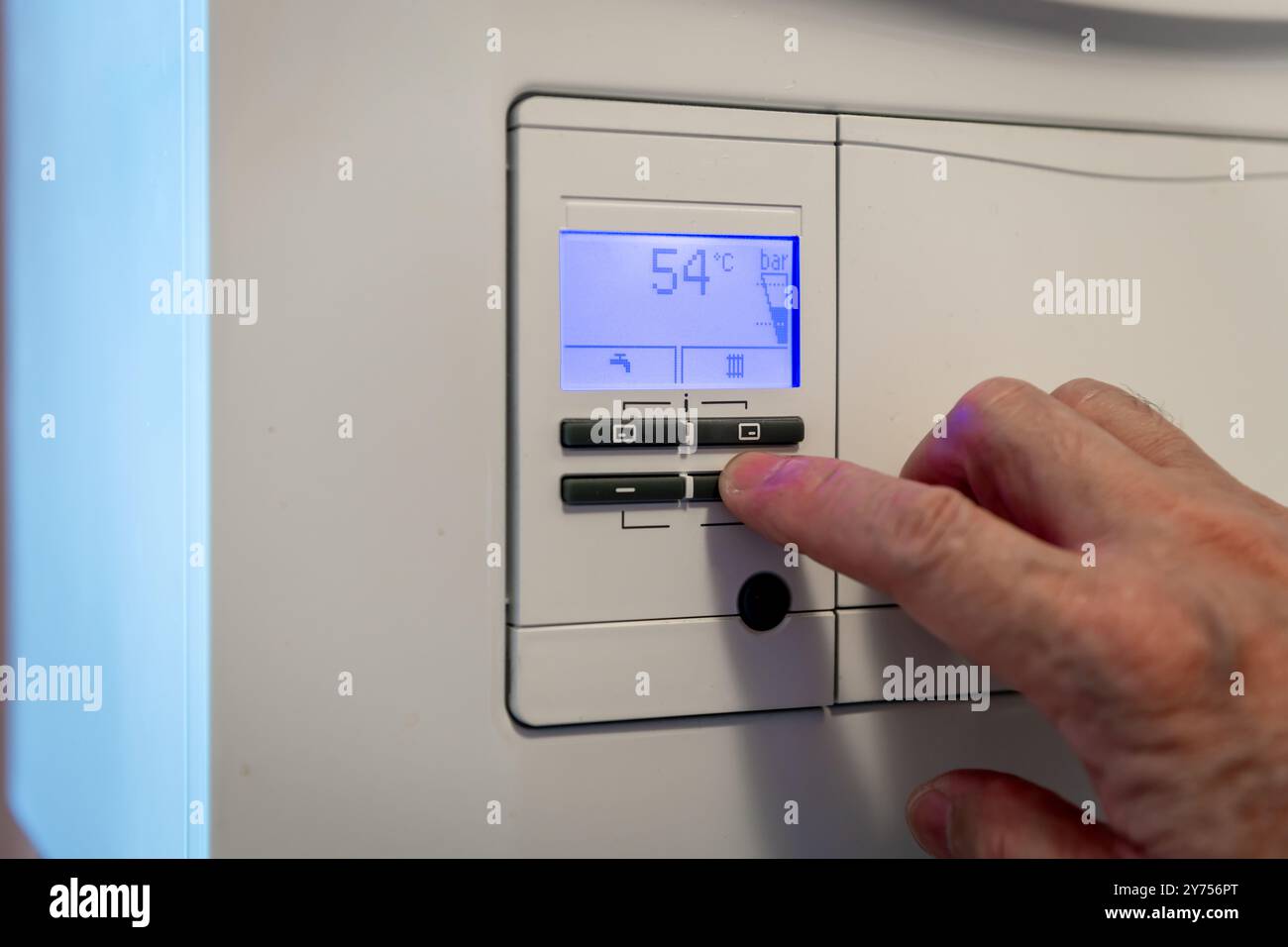 Una persona che regola le varie funzioni di controllo di una caldaia di riscaldamento domestico in preparazione per l'inverno. Un concetto di utilizzo della tecnologia. Foto Stock