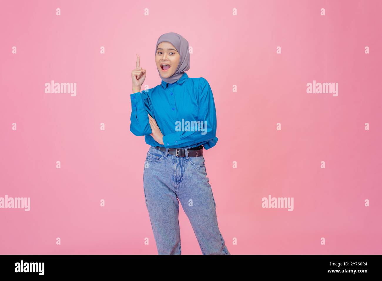 Una giovane donna vestita con una camicia blu ha posato su uno sfondo rosa, mostrando un gesto positivo Foto Stock