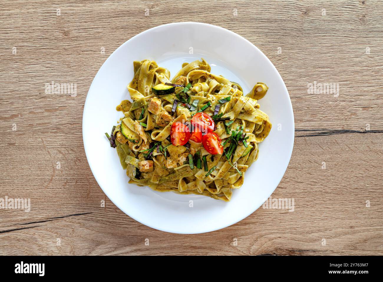 Pesto con tagliatelle con pollo e pomodori ciliegini stesi su un piatto. Foto Stock