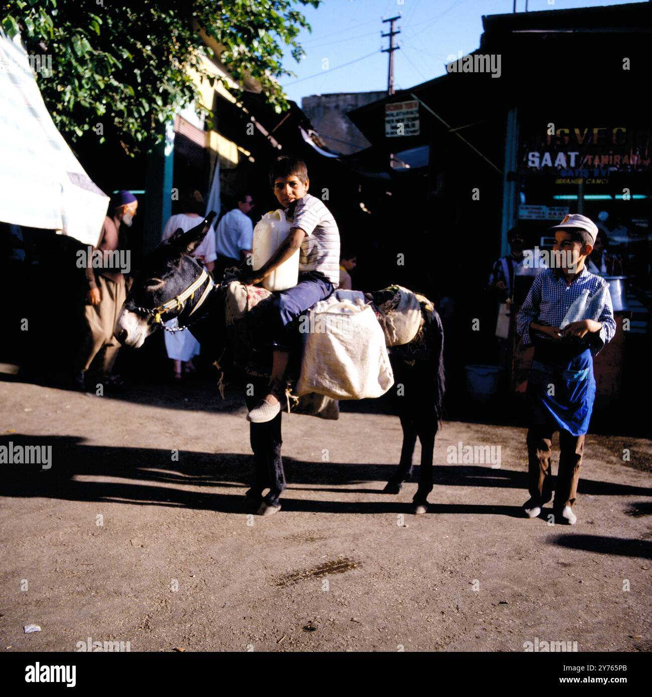 Zwei Jungen, einer mit einem Kanister auf Eselrücken, der andere mit Schürze, in der Stadt Diyarbakir (Diyarbakır) in der gleichnamigen Provinz in Südostanatolien, Türkei um 1988. Foto Stock