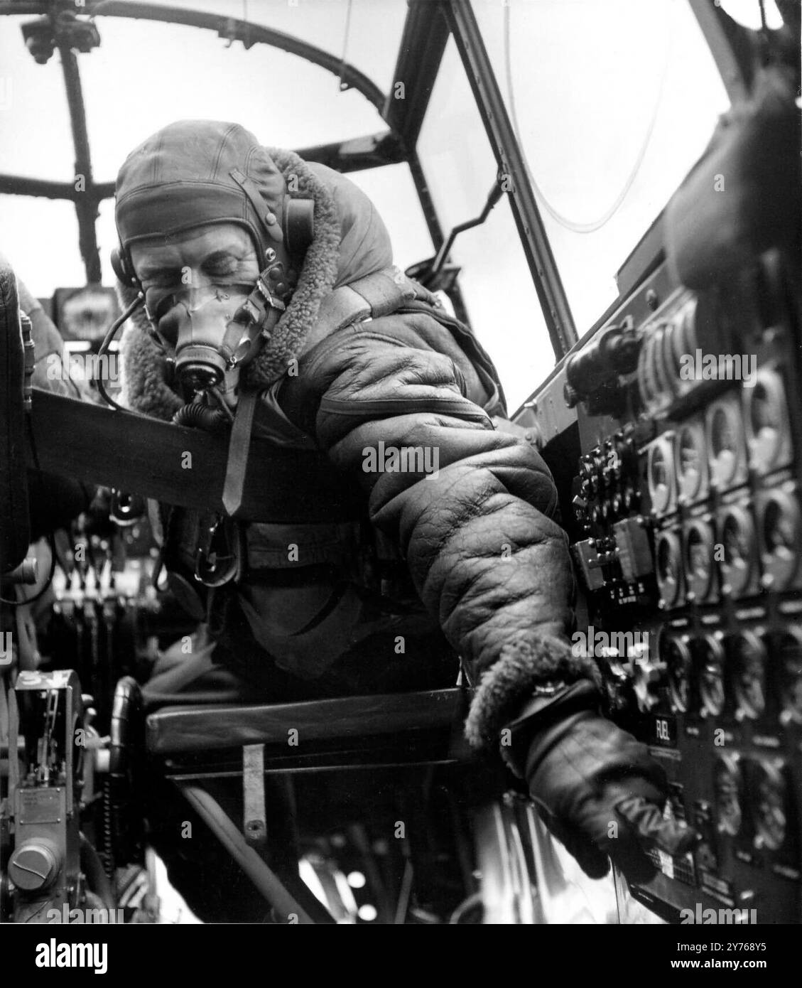 Un ingegnere di volo Lancaster nella cabina di pilotaggio di un Avro Lancaster Bomber, noto anche come Lancs, era un bombardiere pesante della seconda guerra mondiale adottato dalla Royal Air Force (RAF). Originariamente sviluppato come evoluzione del Manchester (che si era rivelato problematico in servizio e fu ritirato nel 1942), il Lancaster fu progettato da Roy Chadwick e motorizzato da quattro Rolls-Royce Merlin. Fu impiegato per la prima volta con il Bomber Command della RAF nel 1942 e, quando l'offensiva strategica dei bombardamenti sull'Europa crebbe slancio, fu l'aereo principale per le campagne di bombardamento notturno che seguirono. Foto Stock