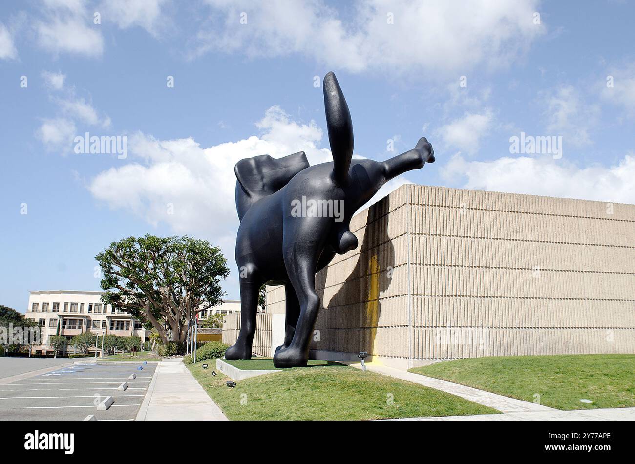 Questa suggestiva scultura raffigura un cane nero gigante che urina giocosamente sul muro dell'edificio. Una dichiarazione umoristica e audace dell'artista Richard Jackson. Foto Stock