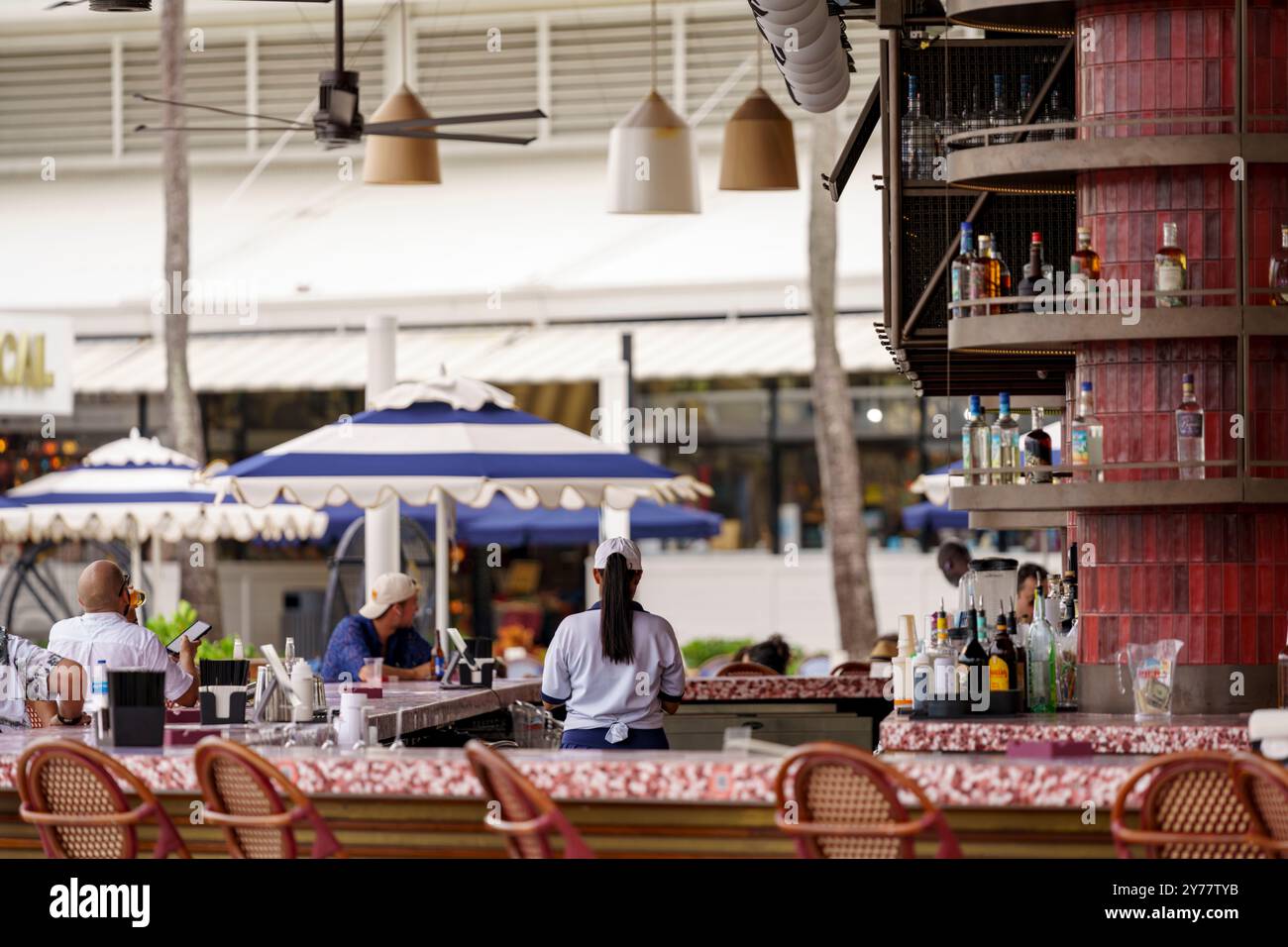 Miami, FL, USA - 25 settembre 2024: Il tender del bar tende agli ospiti seduti al bar Foto Stock
