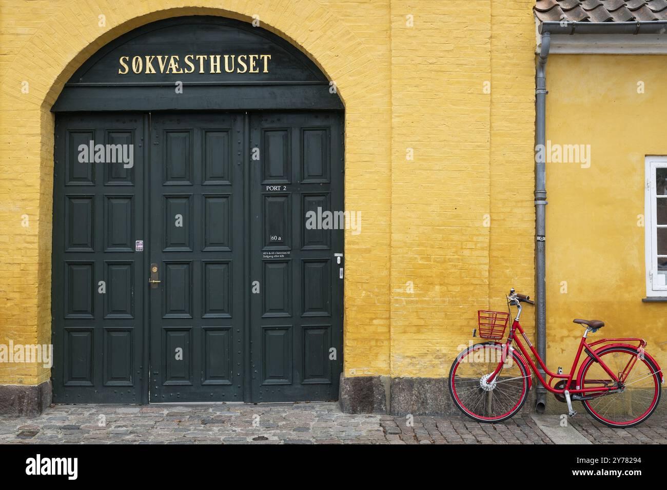 Bicicletta rossa di fronte alle mura gialle, ingresso all'edificio protetto dal patrimonio culturale Sokvaesthuset, ex ospizio navale, Christianshavn Canal, Christianshav Foto Stock