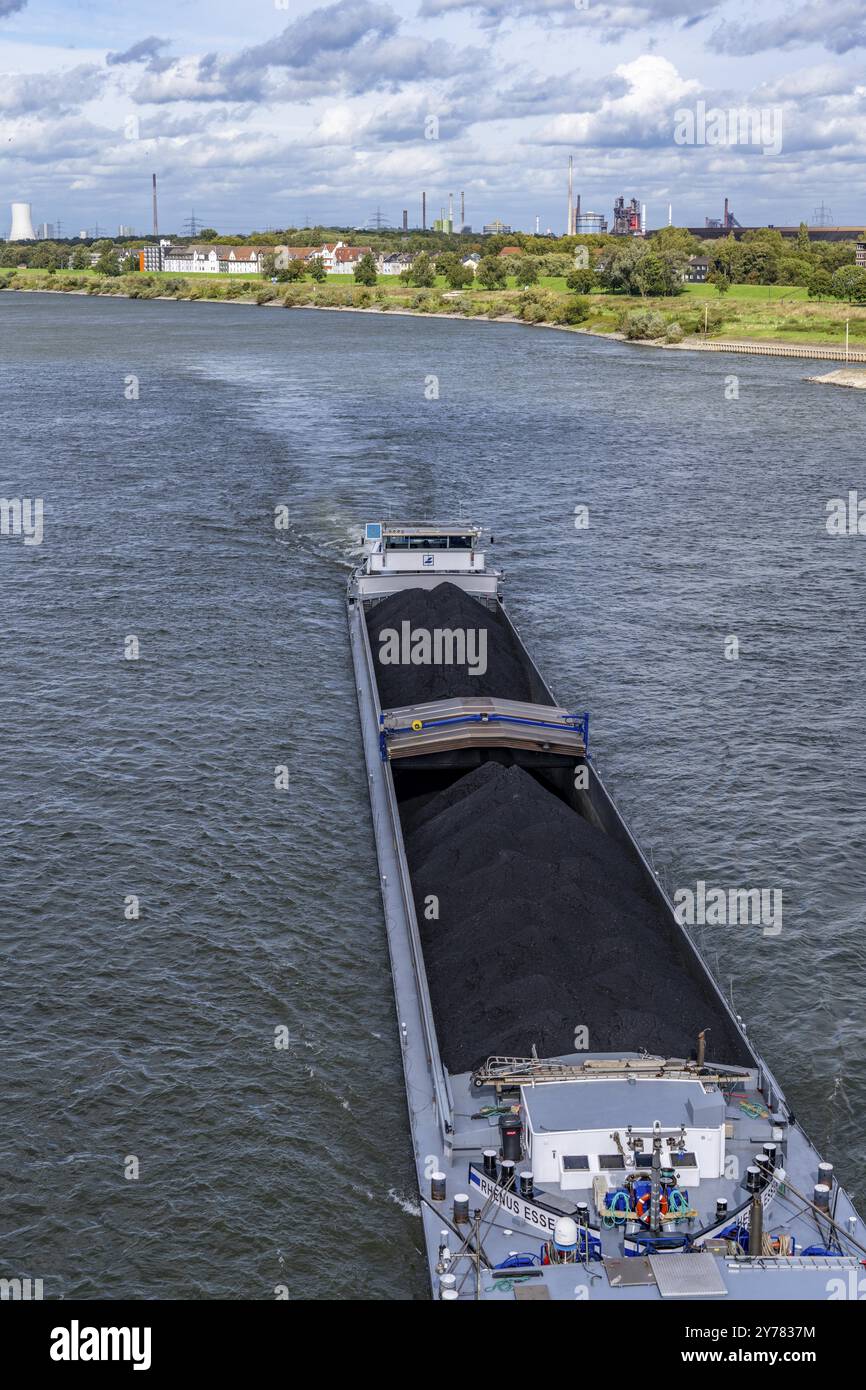 Reno vicino a Duisburg-Laar, cargo carico di carbone, case sulla strada diga, sfondo industriale della acciaieria ThyssenKrupp a Bruckhausen Foto Stock