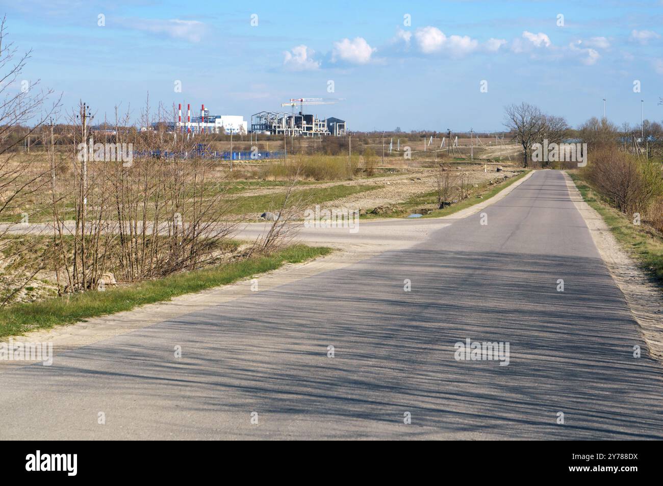 Strada secondaria di campagna, in lontananza la costruzione dell'impianto Foto Stock