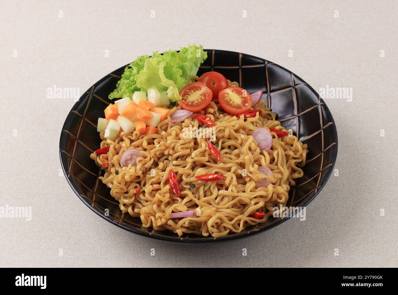 Indomie Goreng piccante, popolare spaghetti istantanei indonesiani con lattuga e pomodoro Foto Stock
