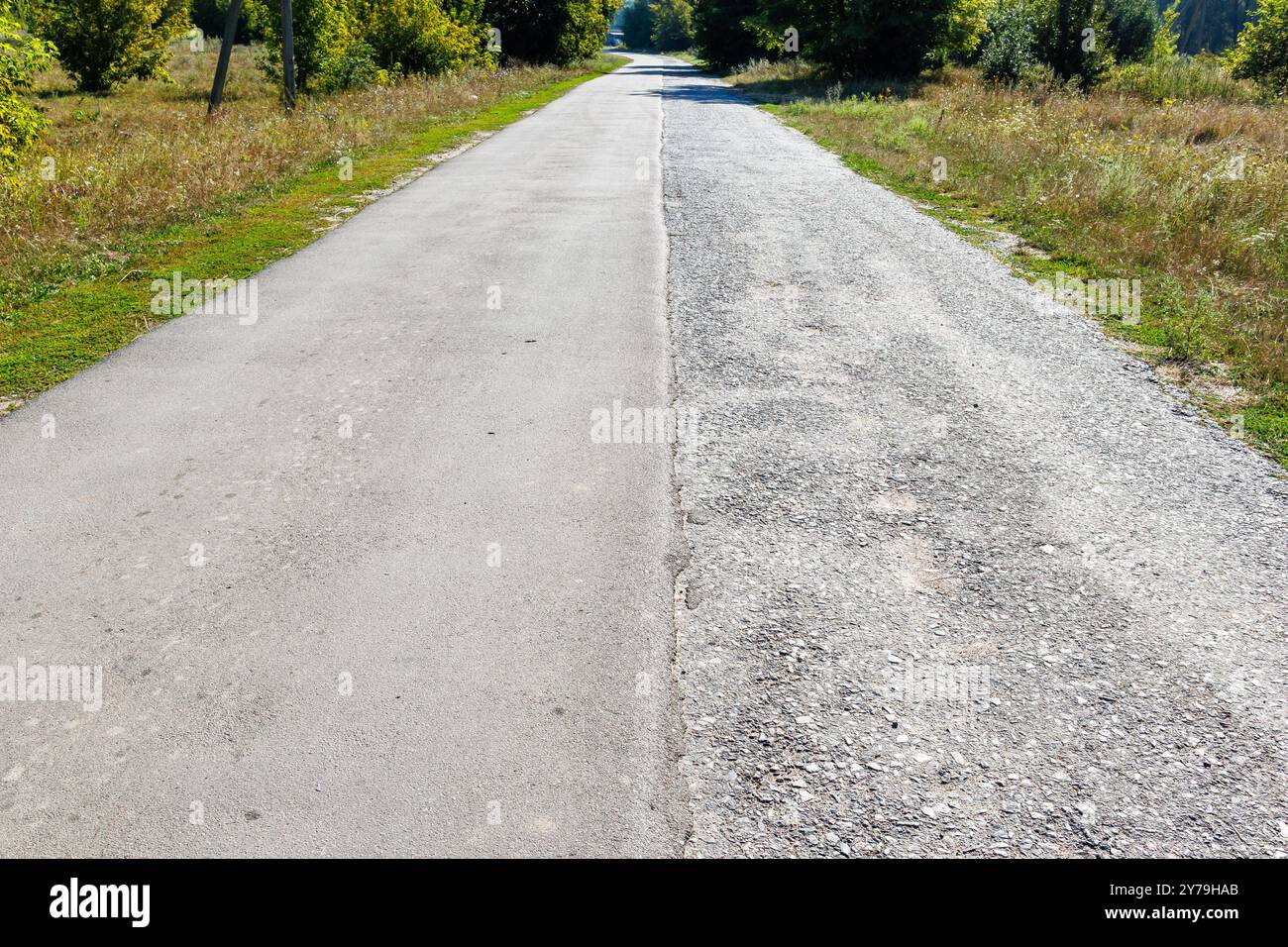 Una strada di importanza locale con due corsie di traffico, la metà delle quali è coperta da nuovo asfalto per migliorare la sicurezza del traffico. Mezzo vecchio, mezzo n Foto Stock