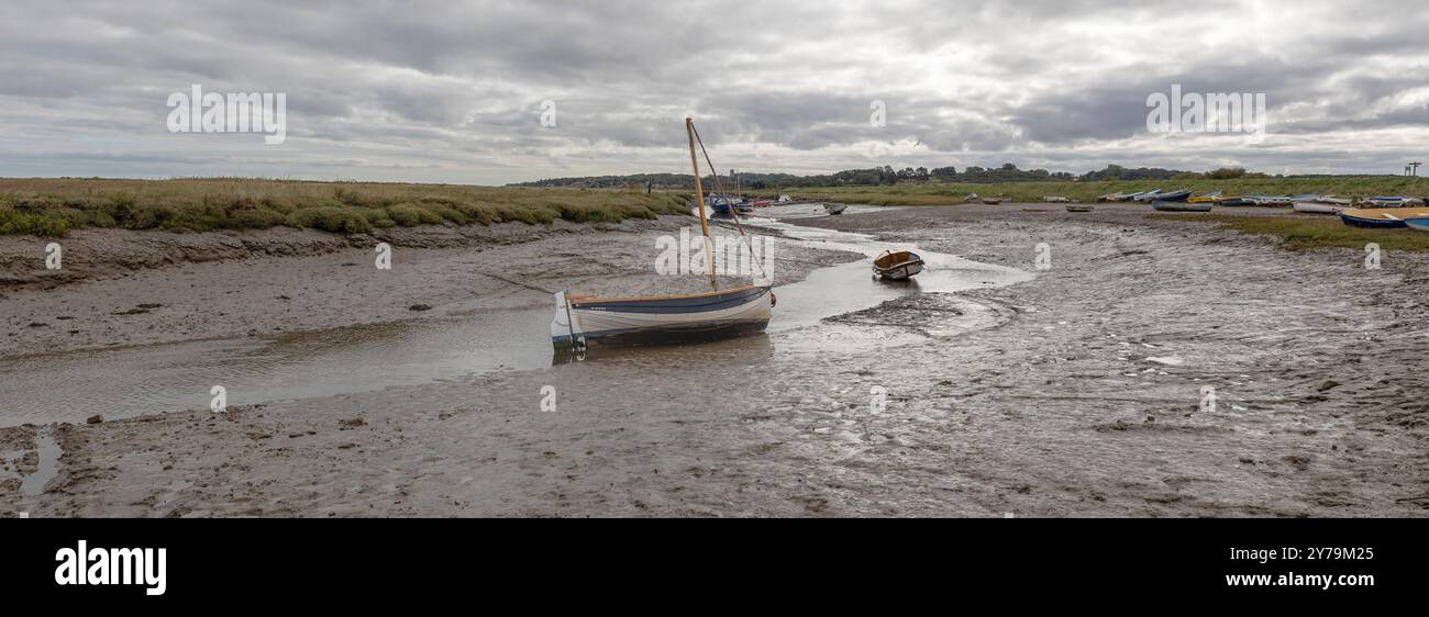 Una vista grandangolare del molo di Morston a Norfolk. La marea è fuori e le piccole barche sono lasciate a terra sulle rive. Foto Stock
