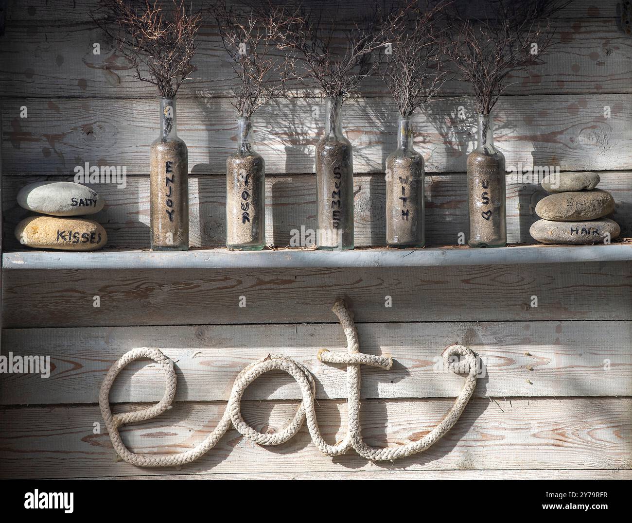 Arte murale in stile elegante e squallido nel ristorante costiero greco, con il tempo e il tempo battuto, insegna in legno "EAT" con disposizione degli angoli cottura nella taverna greca Foto Stock