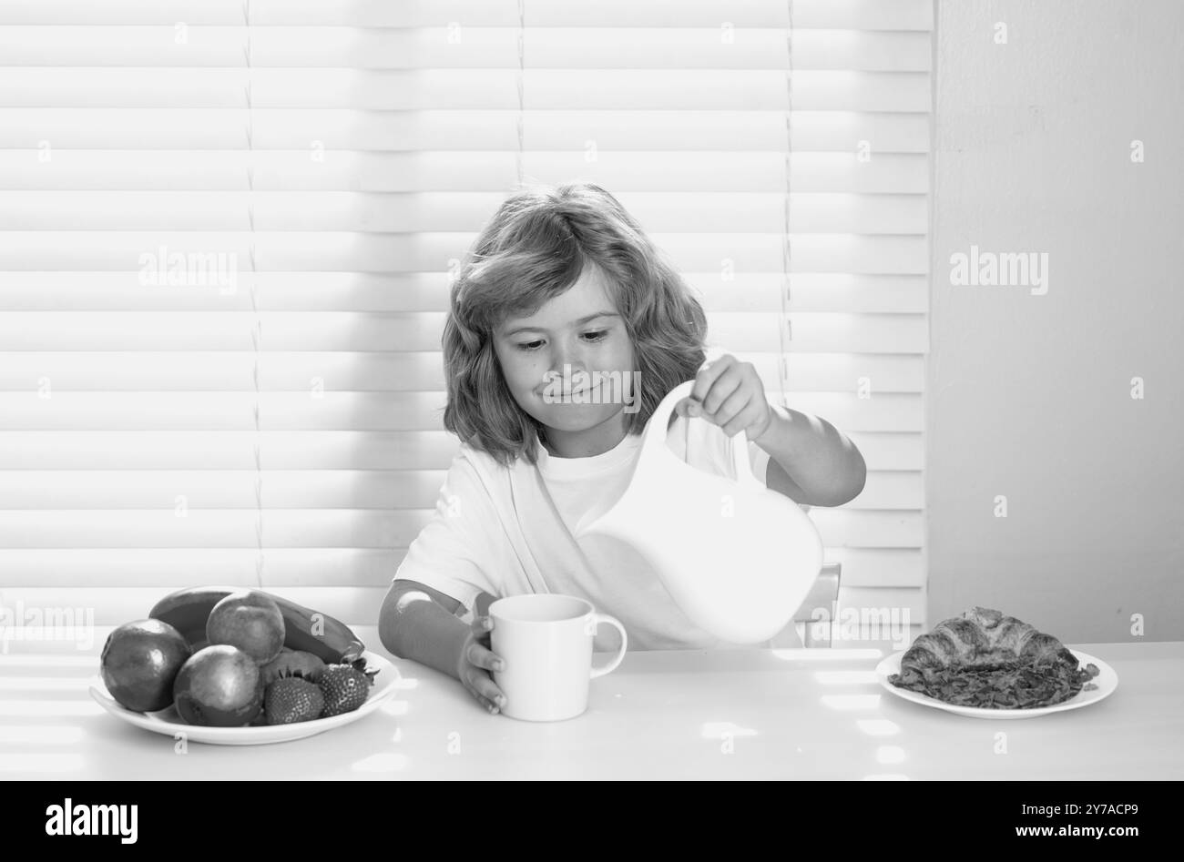 Carino bambino versando latte intero di mucche. Ritratto di bambino mangiare cibo fresco sano in cucina a casa. Bambino che mangia la colazione prima della scuola. Foto Stock